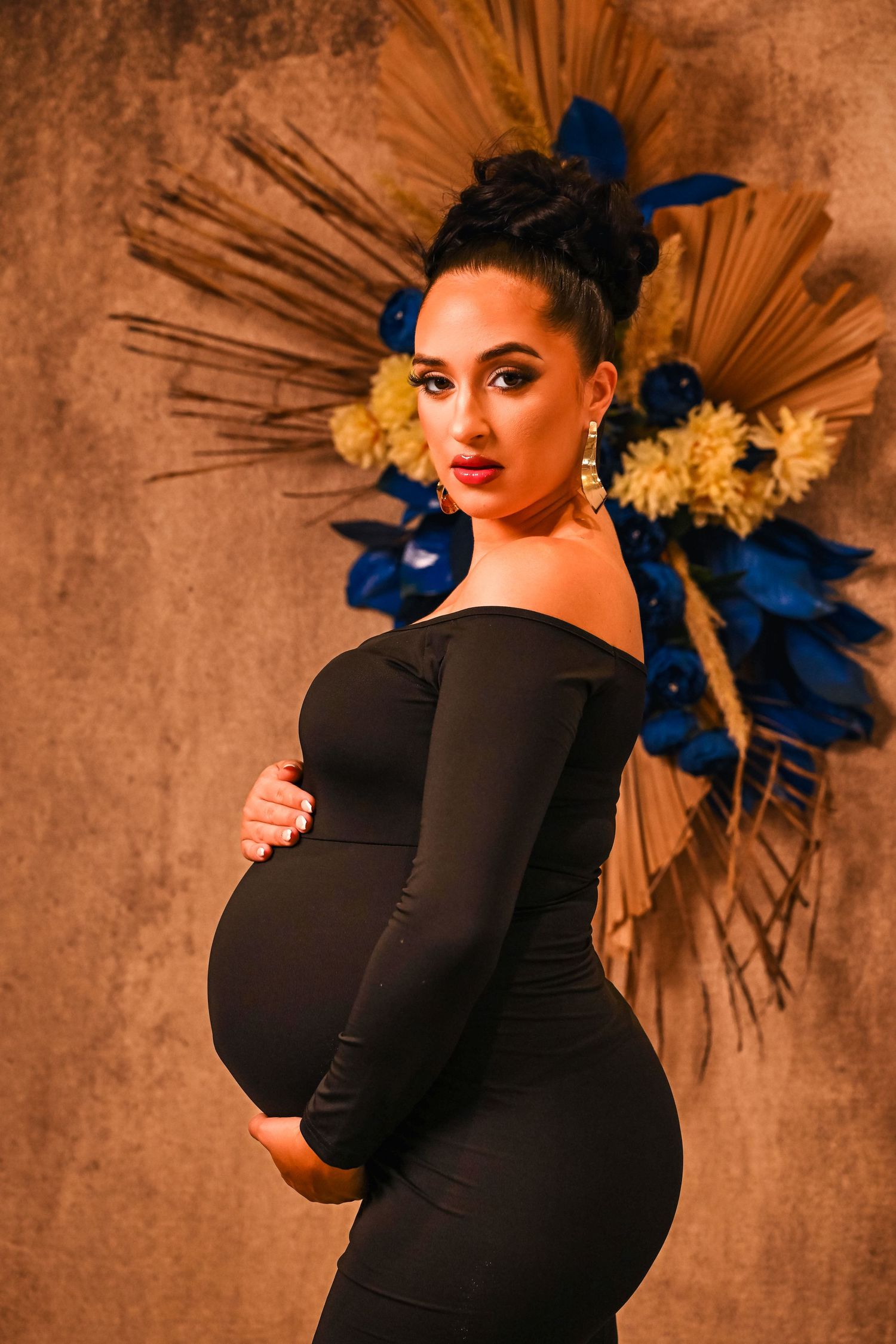Expectant mother in a fitted black dress poses with confidence at maternity portrait session by South Florida portrait photographer