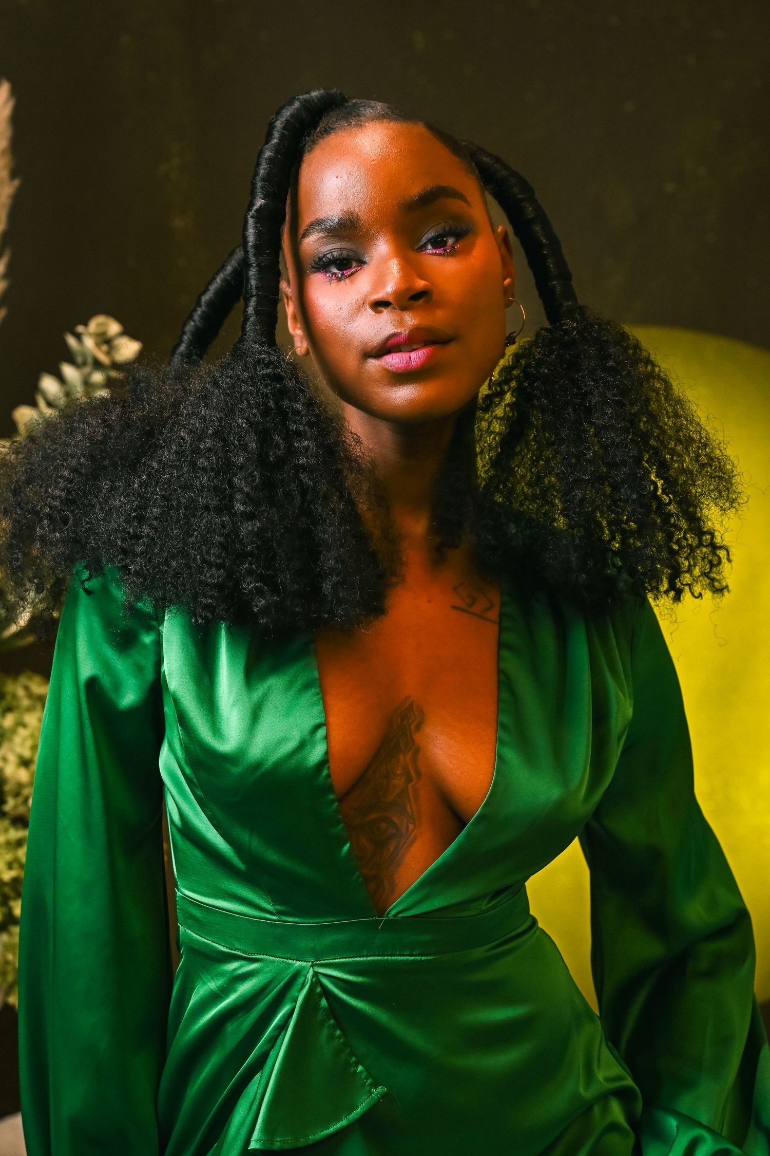 Woman stands confidently in a green gown, with florals in the background, showcasing modern portraiture by Fort Lauderdale photographer