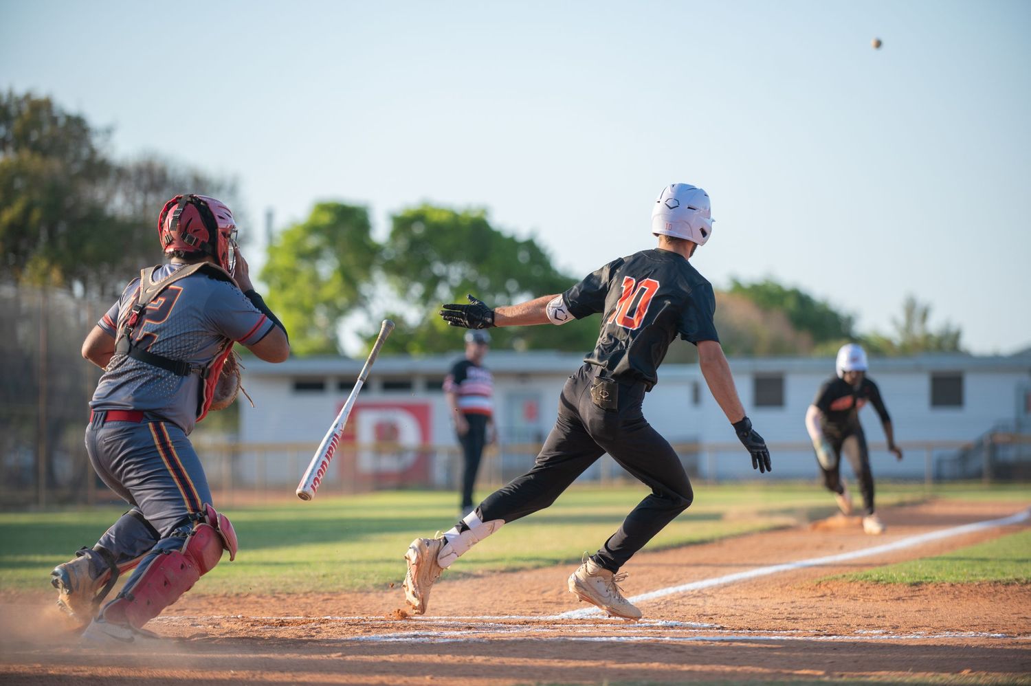 Batter watches ball as it is hit towards third base in the air and runner at third running home. Ur The Focus sports photography - Florida