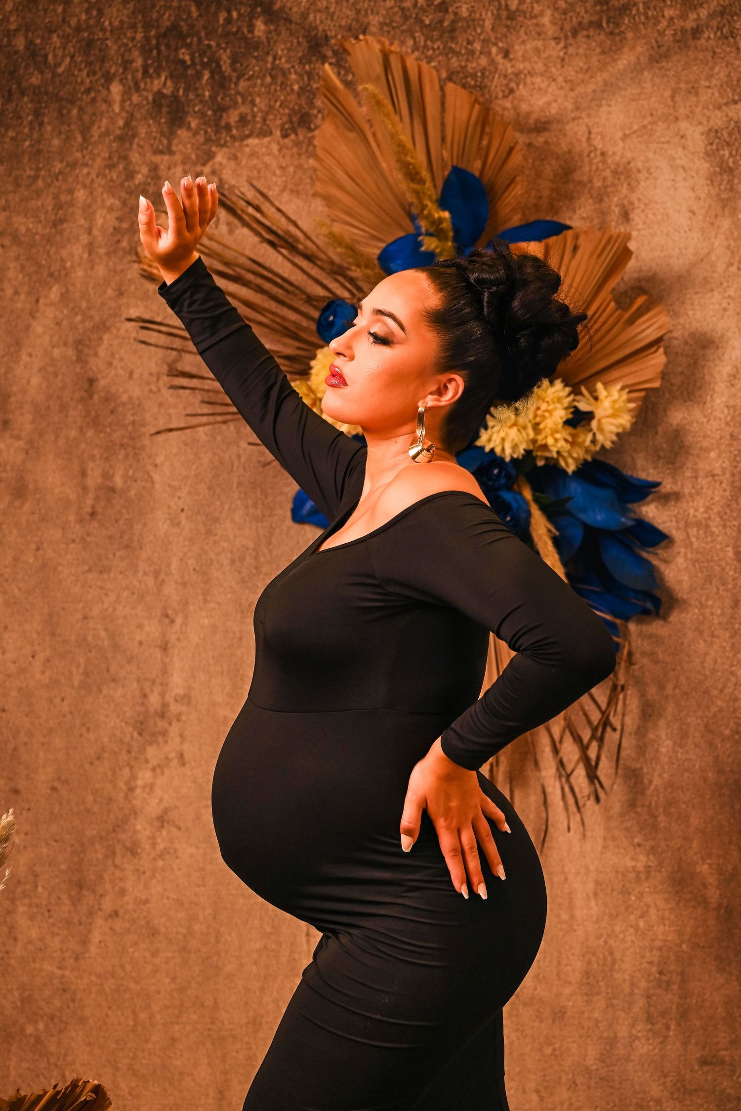 Expectant mother in a fitted black dress poses with confidence at maternity portrait session by Fort Lauderdale portrait photographer