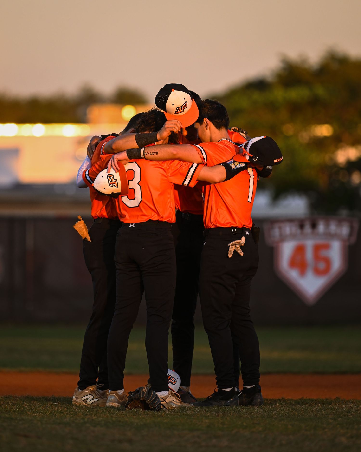 Piper High School baseball team huddles on field at sunset, emphasizing team unity in Fort Lauderdale.
