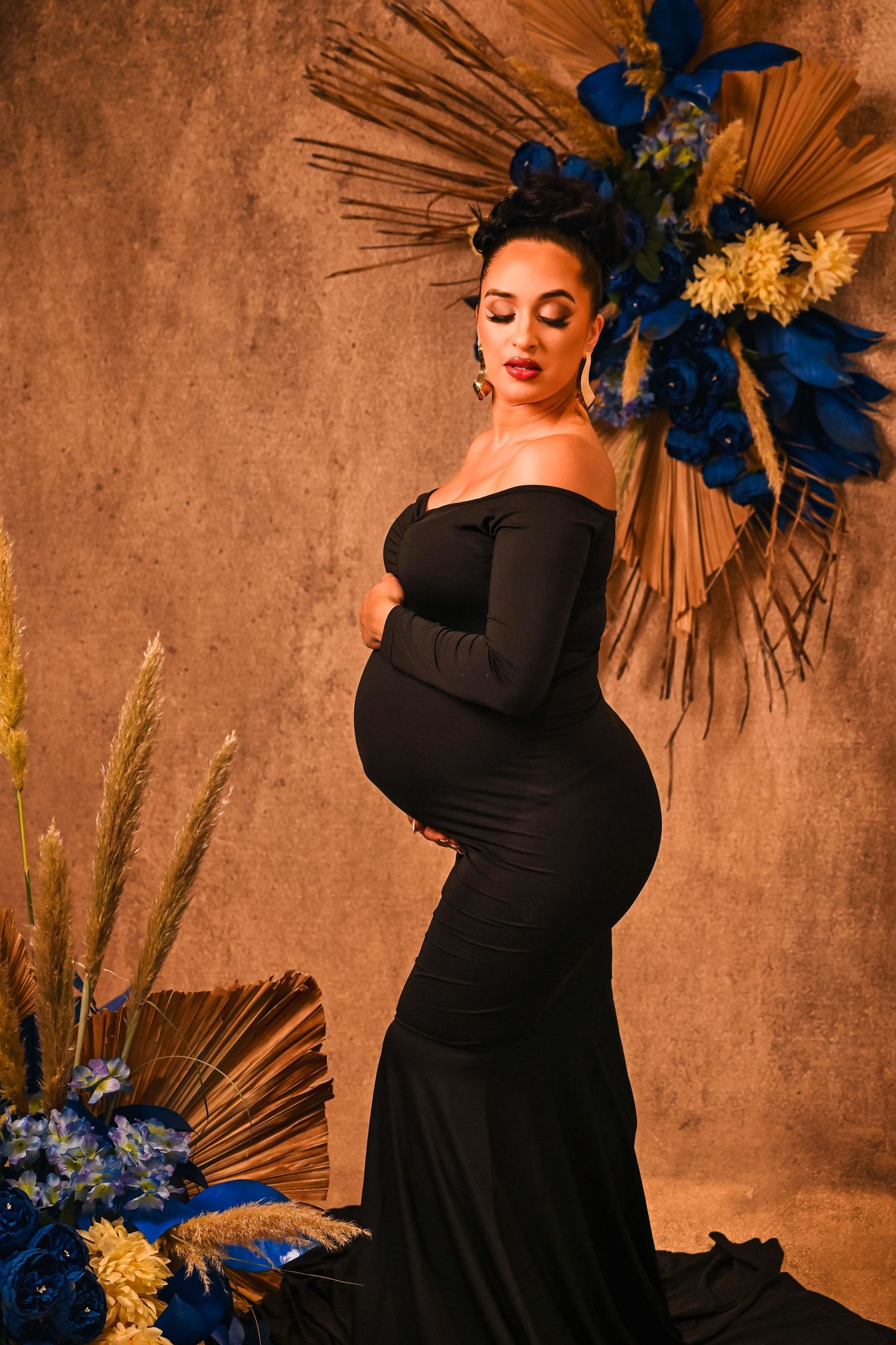 Expectant mother in a fitted black dress poses with confidence at maternity portrait session by Broward County portrait photographer