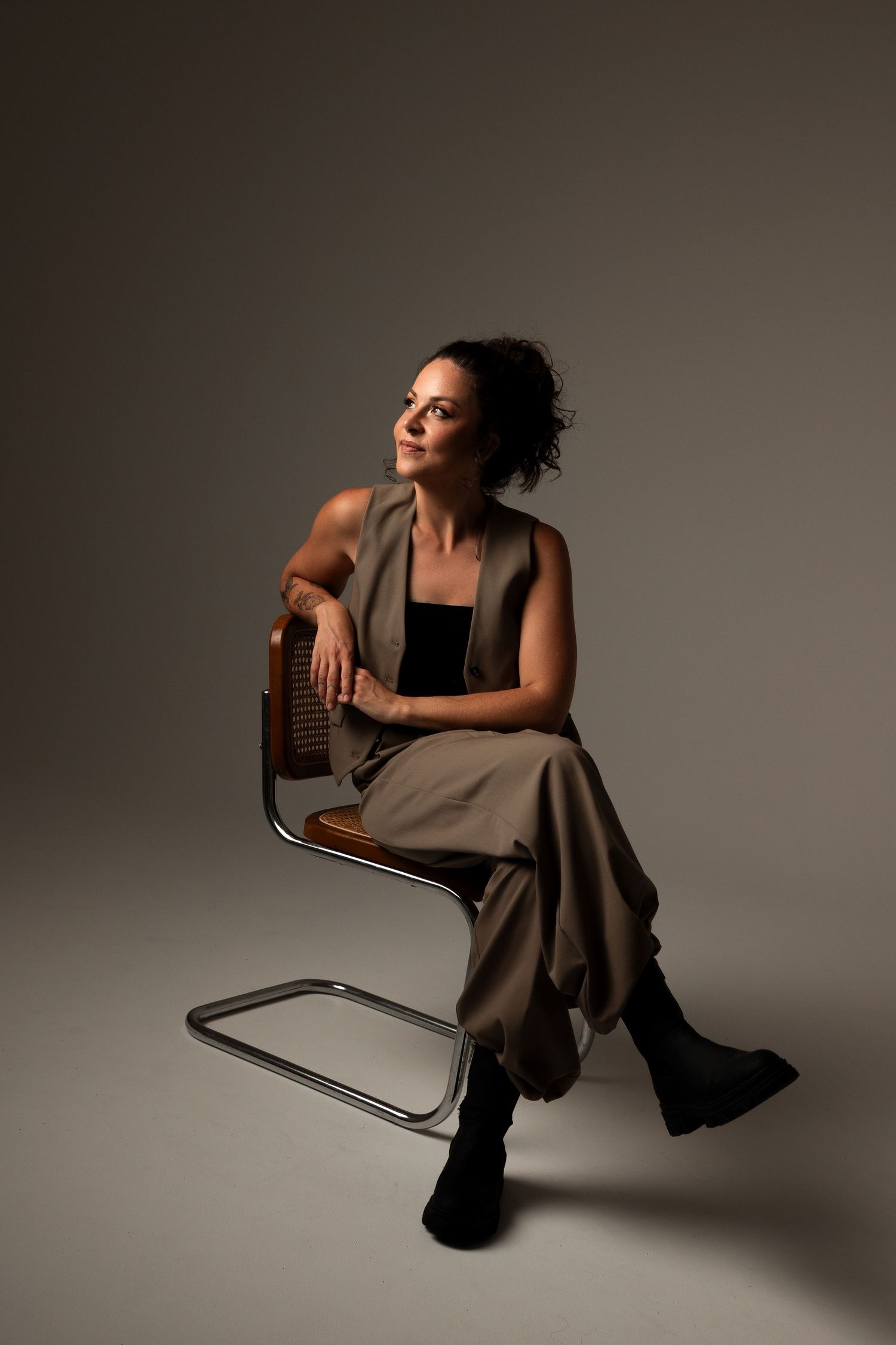 Artistic portrait of someone in casual attire seated on a modern chair in studio lighting.
