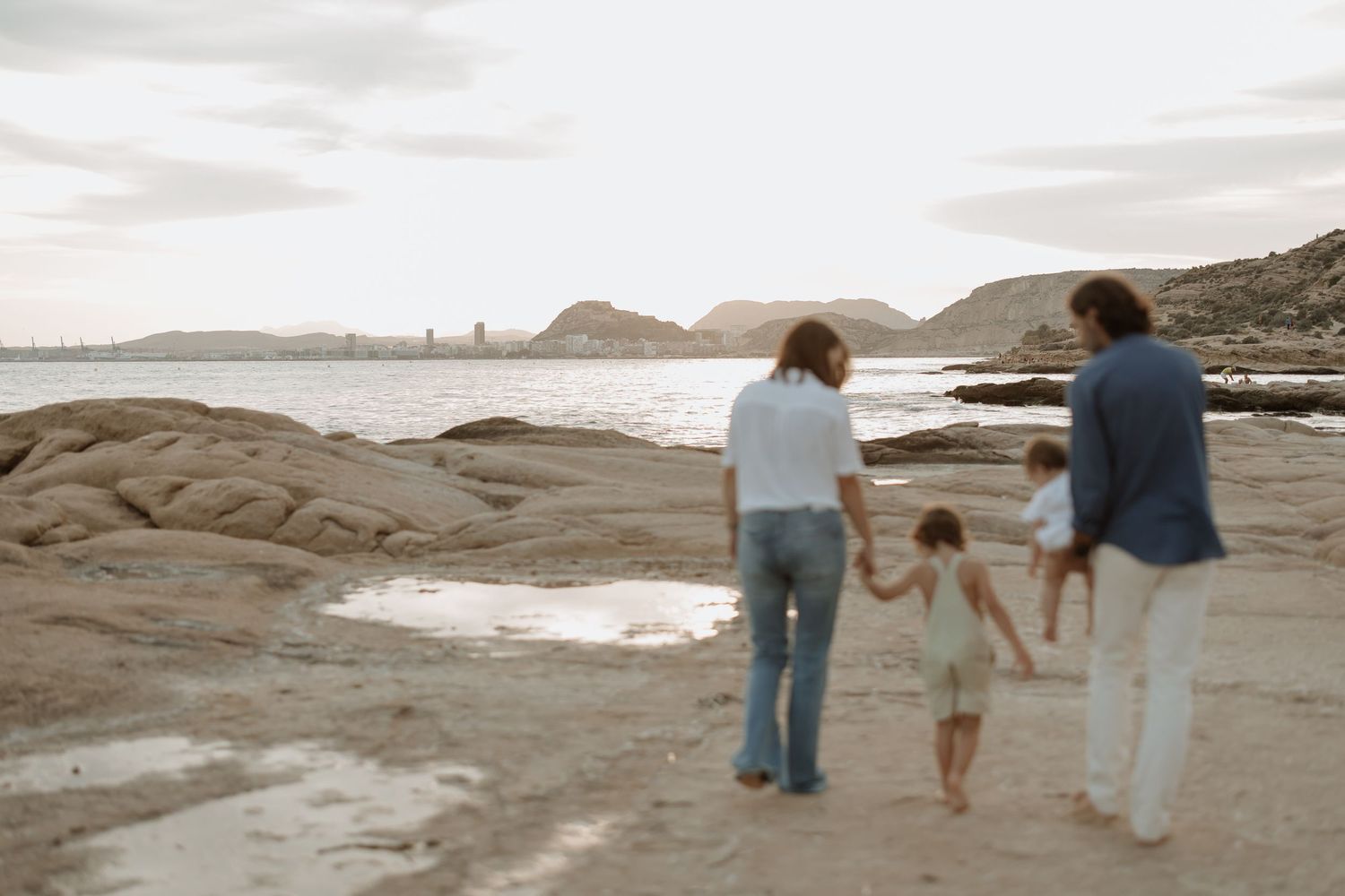 Family enjoys a peaceful walk together on rocky coastal terrain.