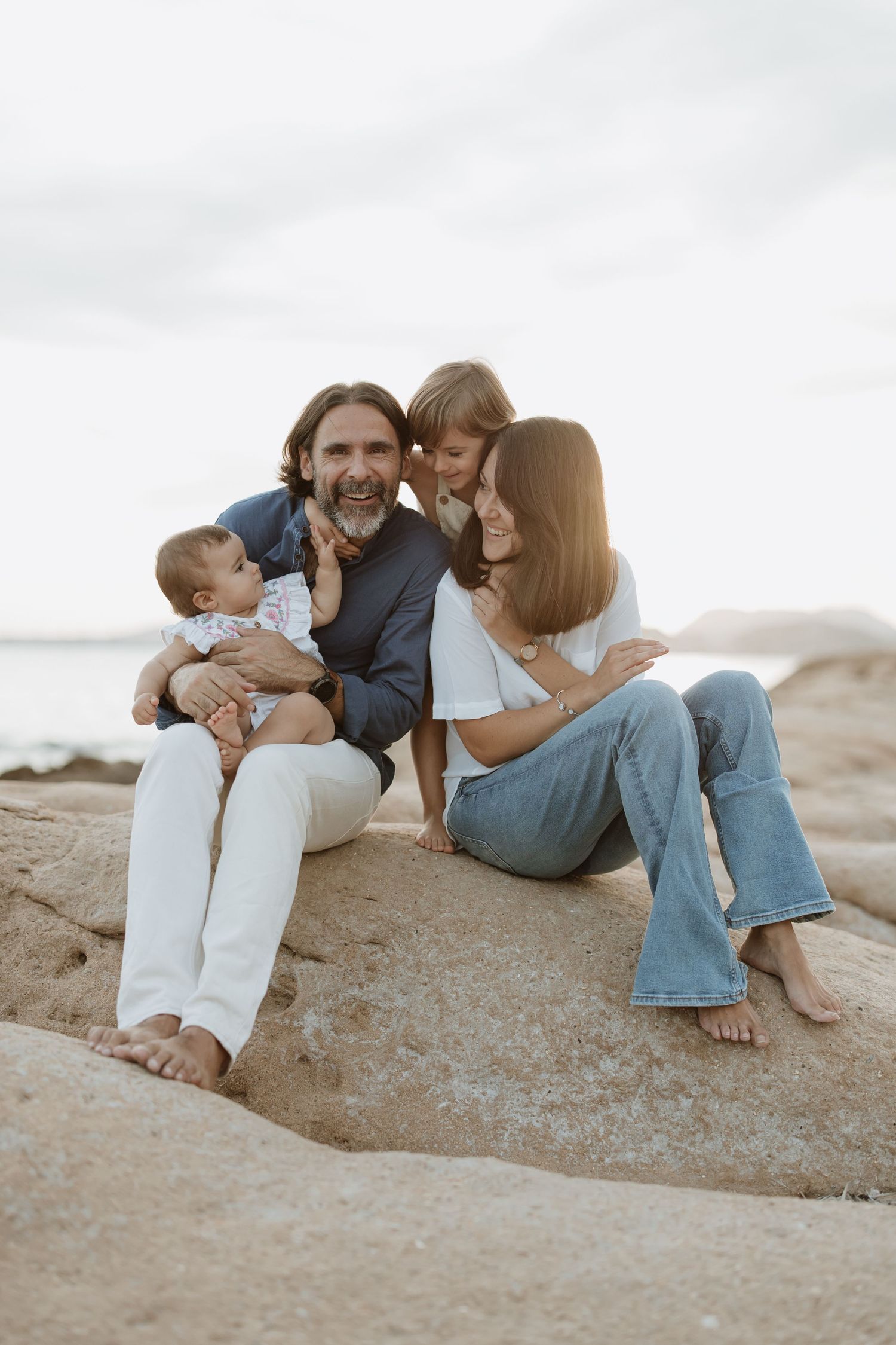 An intimate family portrait showing connection and joy on coastal rocks.