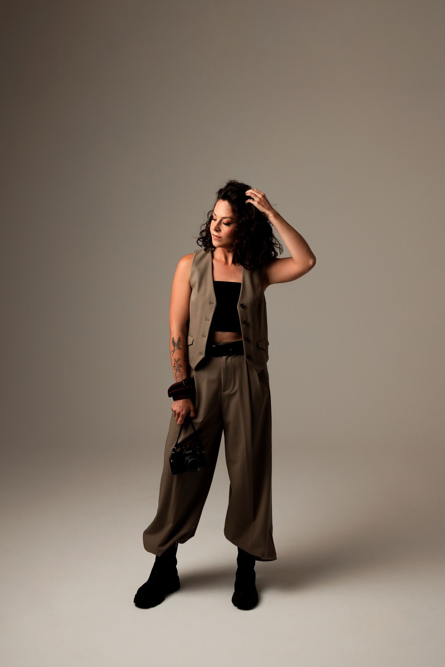 Fashion portrait of someone in olive clothing posing against a neutral studio backdrop.