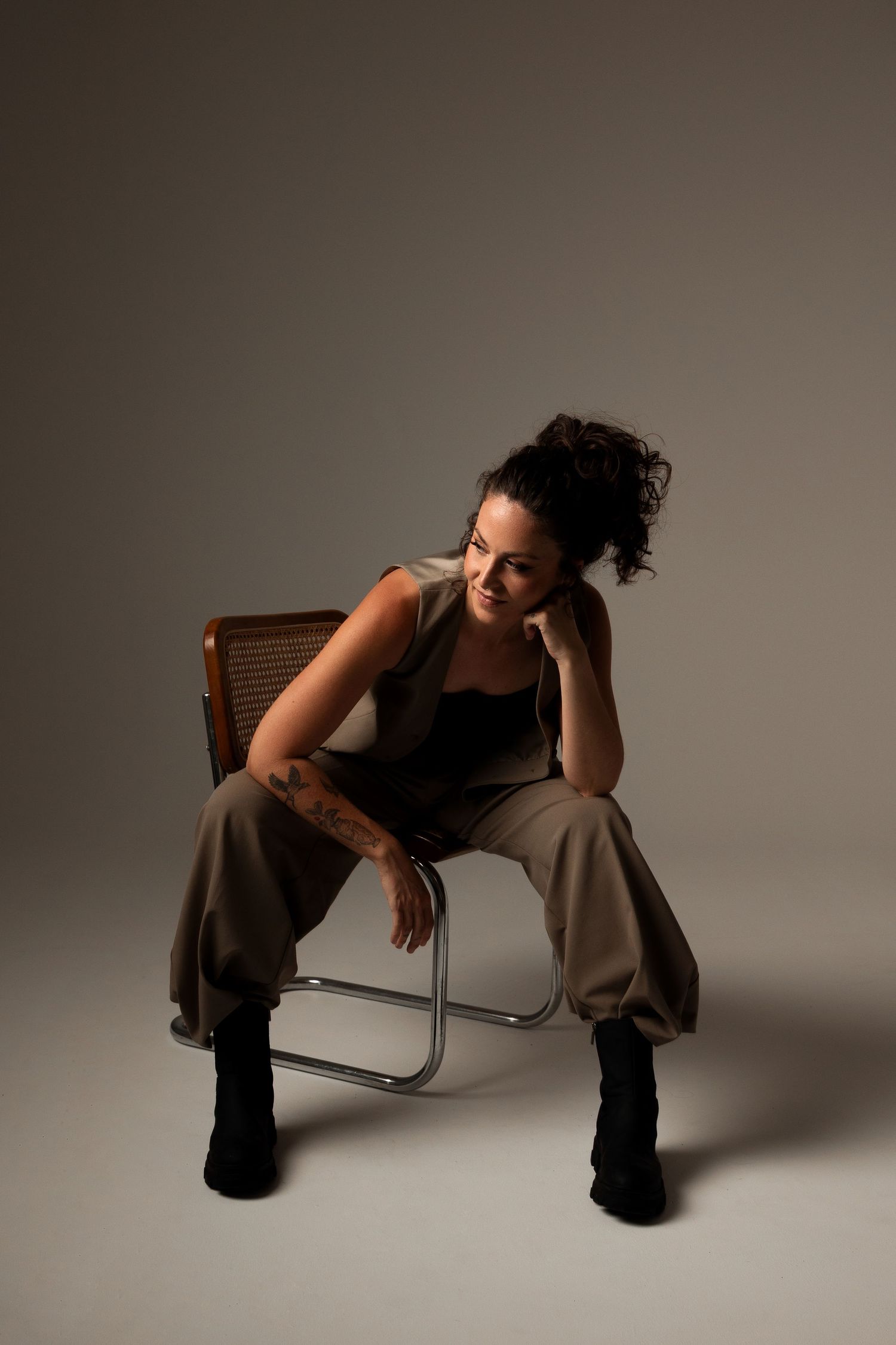 Candid studio shot of someone relaxing in a vintage chair wearing casual attire.