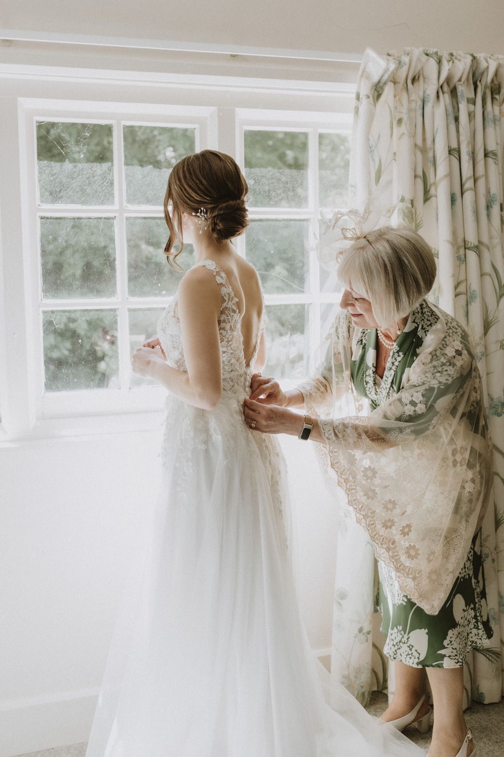 Wedding dress preparations in a sunlit room with delicate lace details.