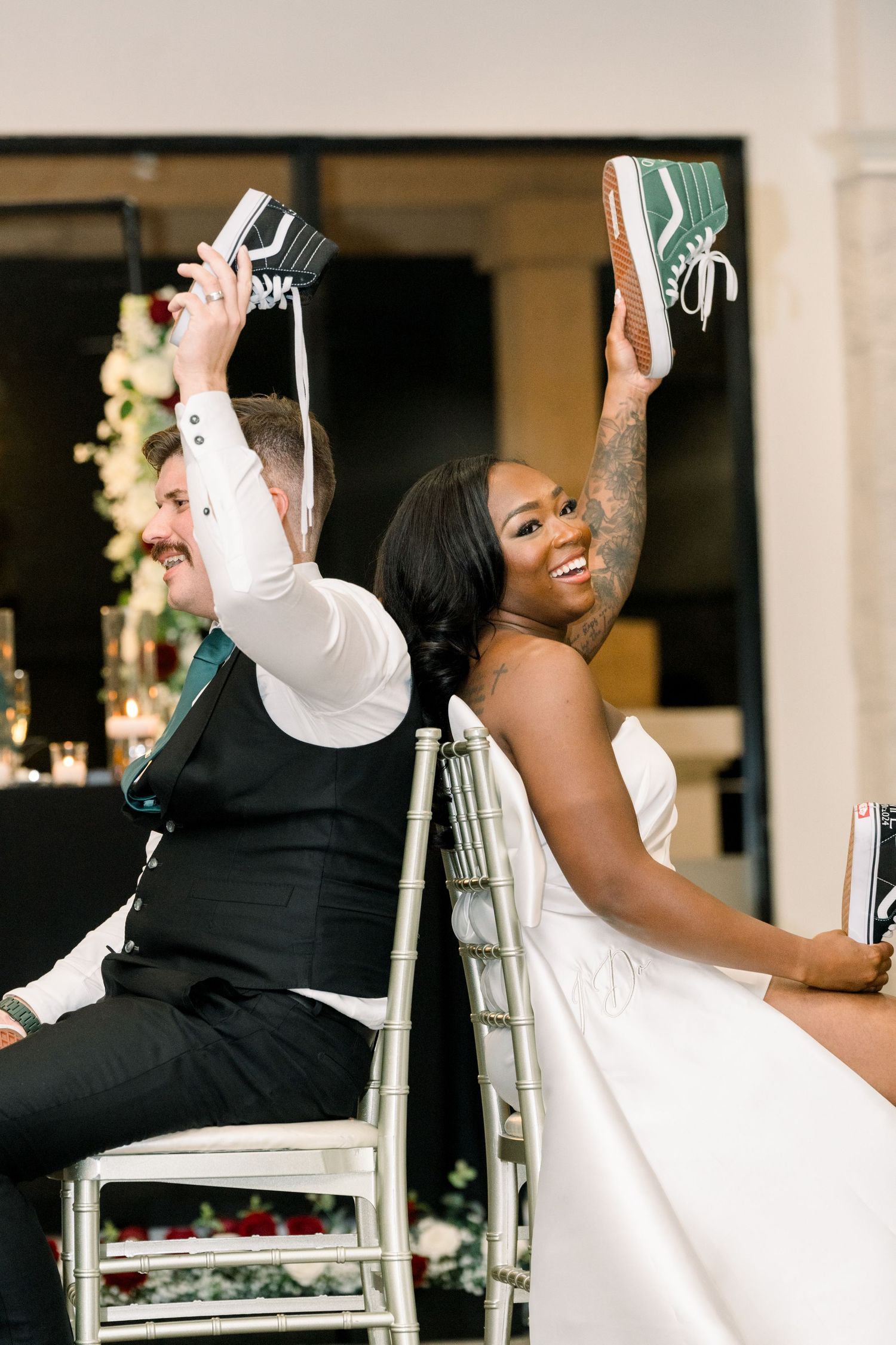 Newlyweds showing off their Vans sneakers while seated at reception.