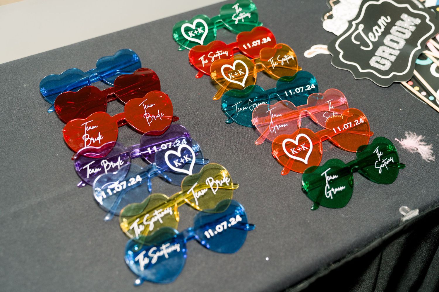 Colorful heart-shaped party sunglasses arranged on dark surface.