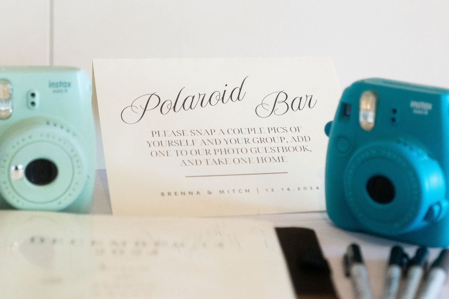 A Polaroid Bar sign displayed between two mint green and turquoise instant cameras.