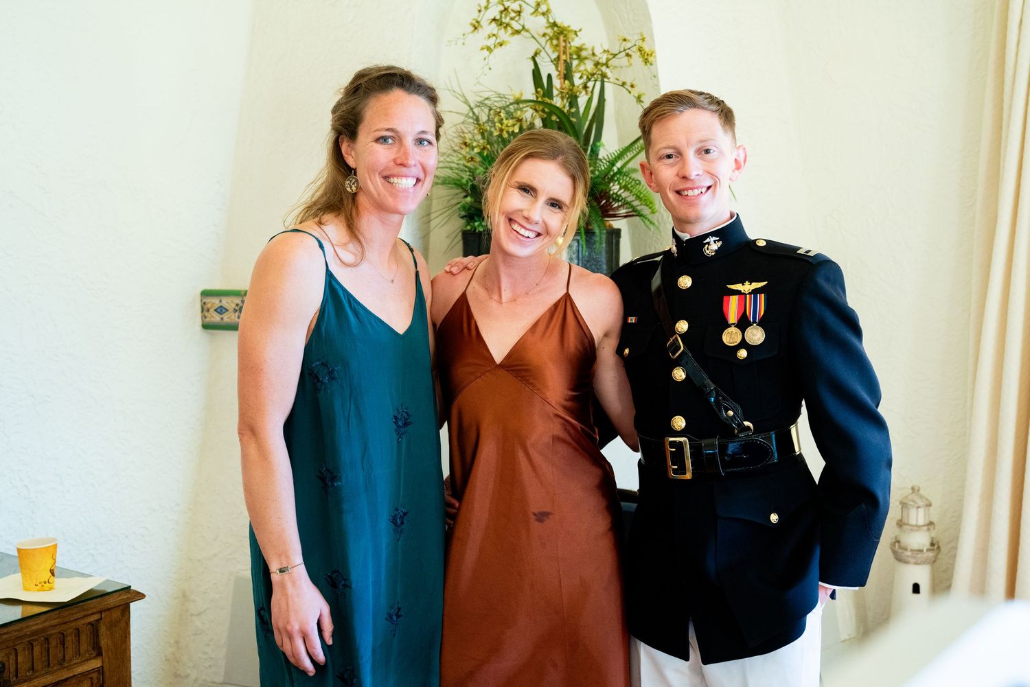 Wedding guests pose together, including someone in formal military dress uniform.