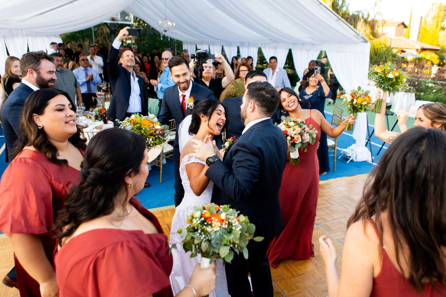Wedding reception under white tent with guests celebrating on blue dance floor.