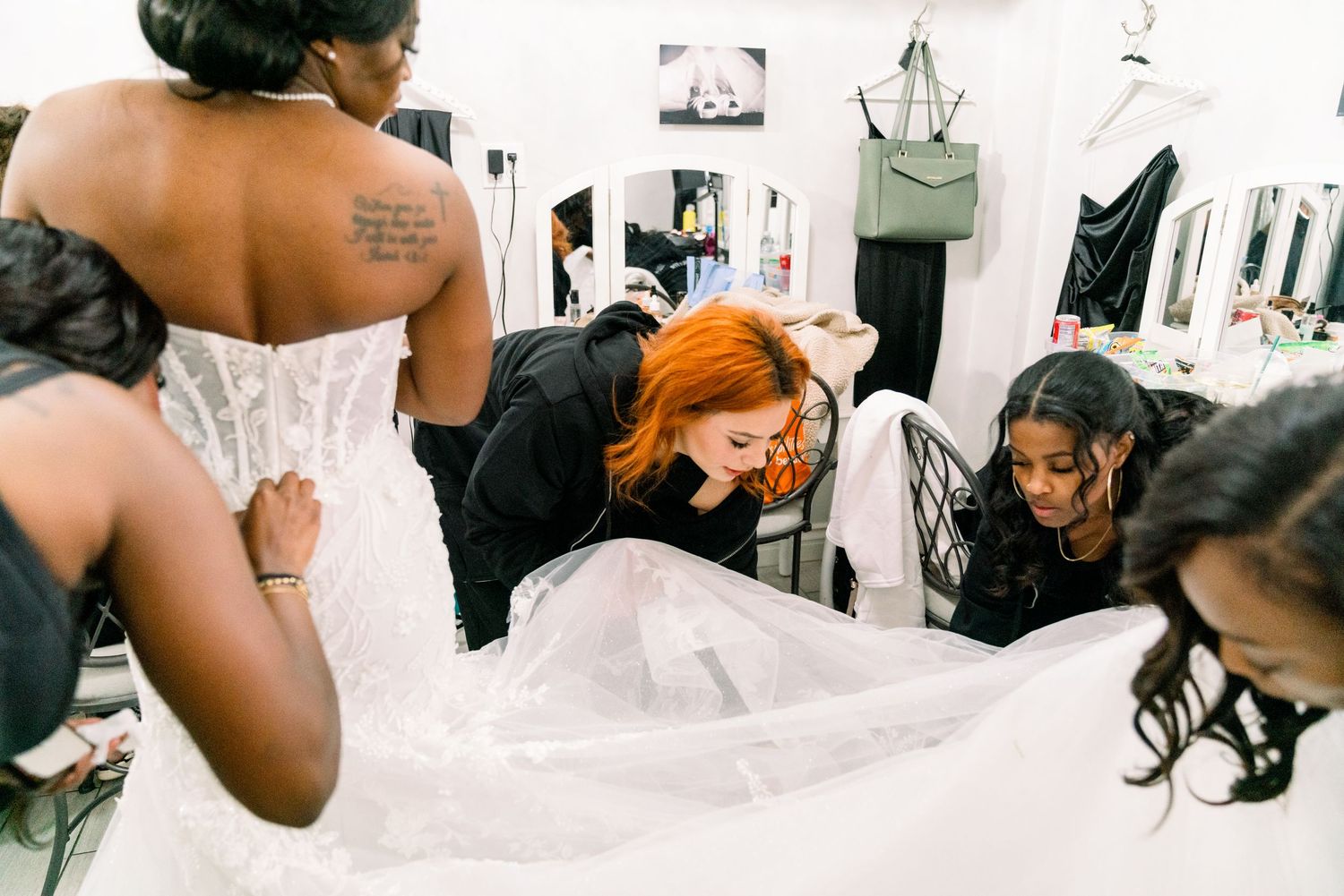 Wedding dress fitting session with multiple people helping adjust the gown's details.
