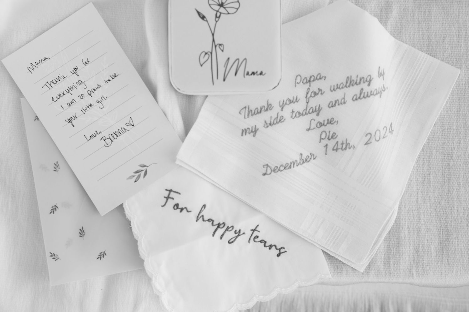 Handwritten notes and cards with personal messages on delicate white paper create an intimate monochromatic composition.