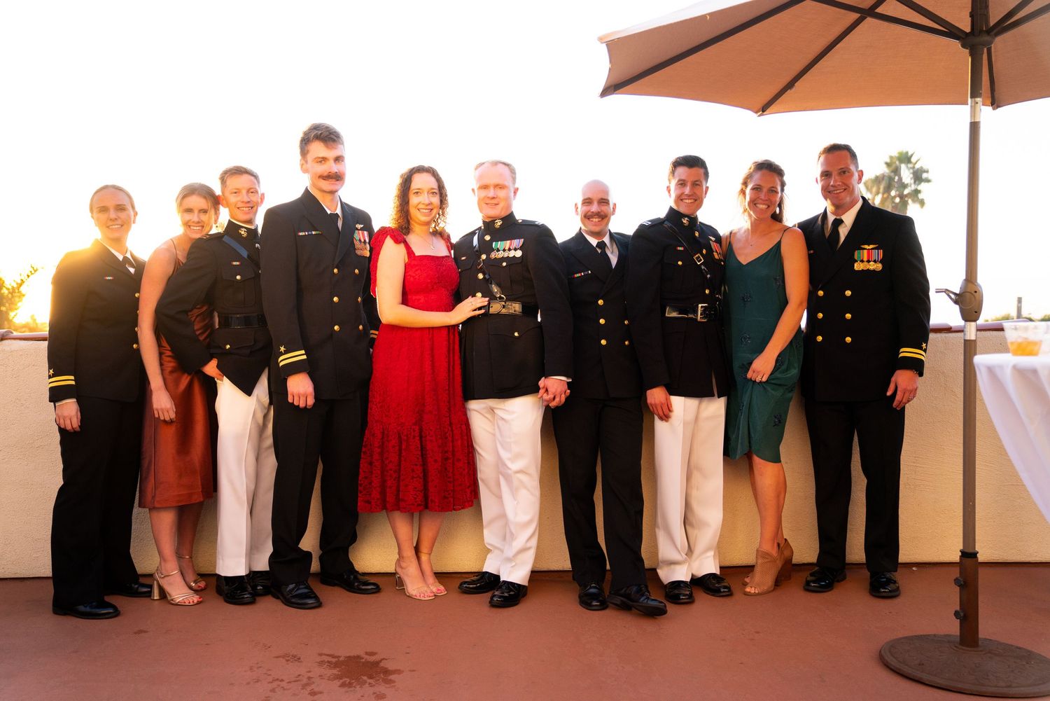 Group photo of military personnel and guests in formal attire at sunset reception.