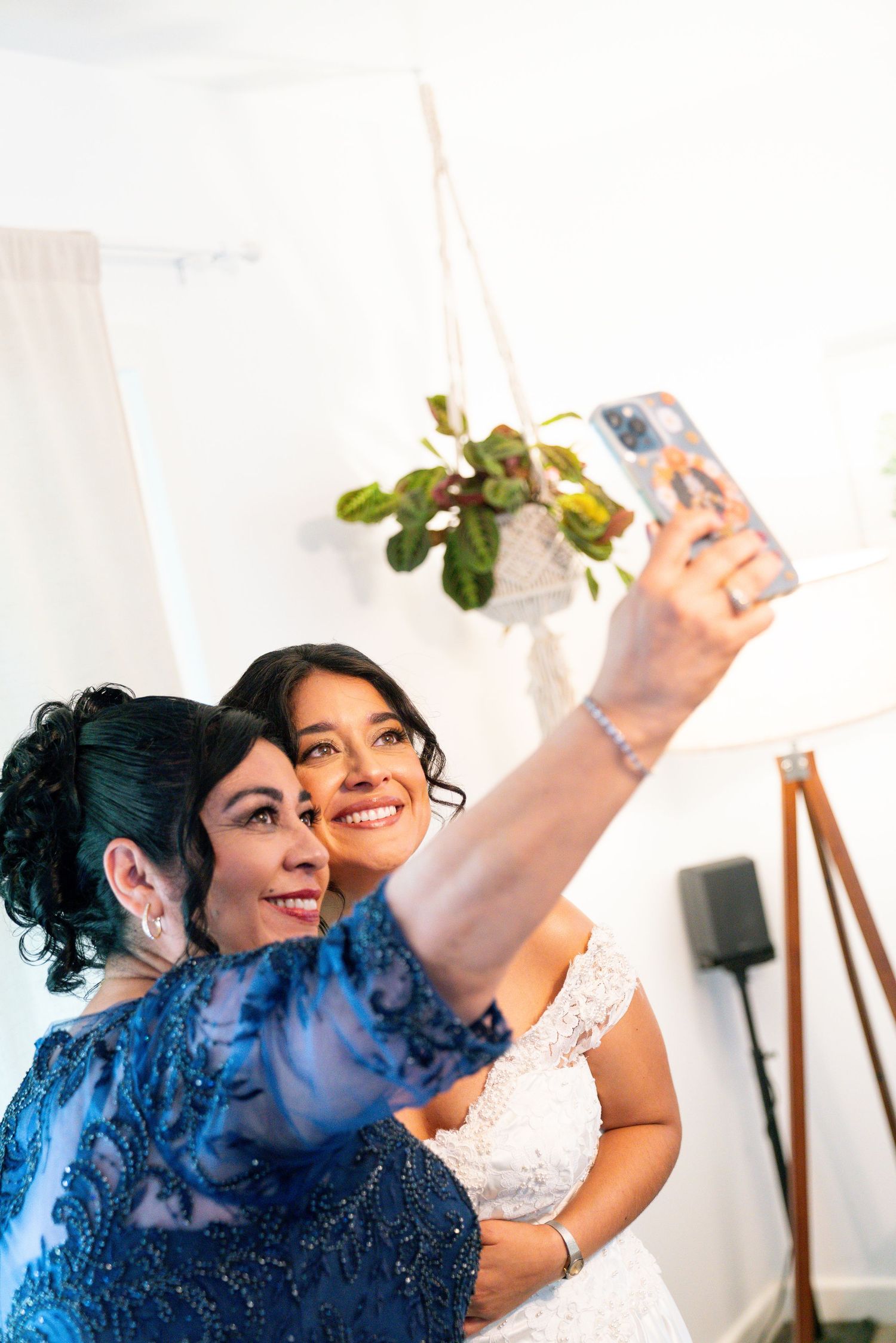 Two women in formal attire taking a selfie together at a wedding celebration event.