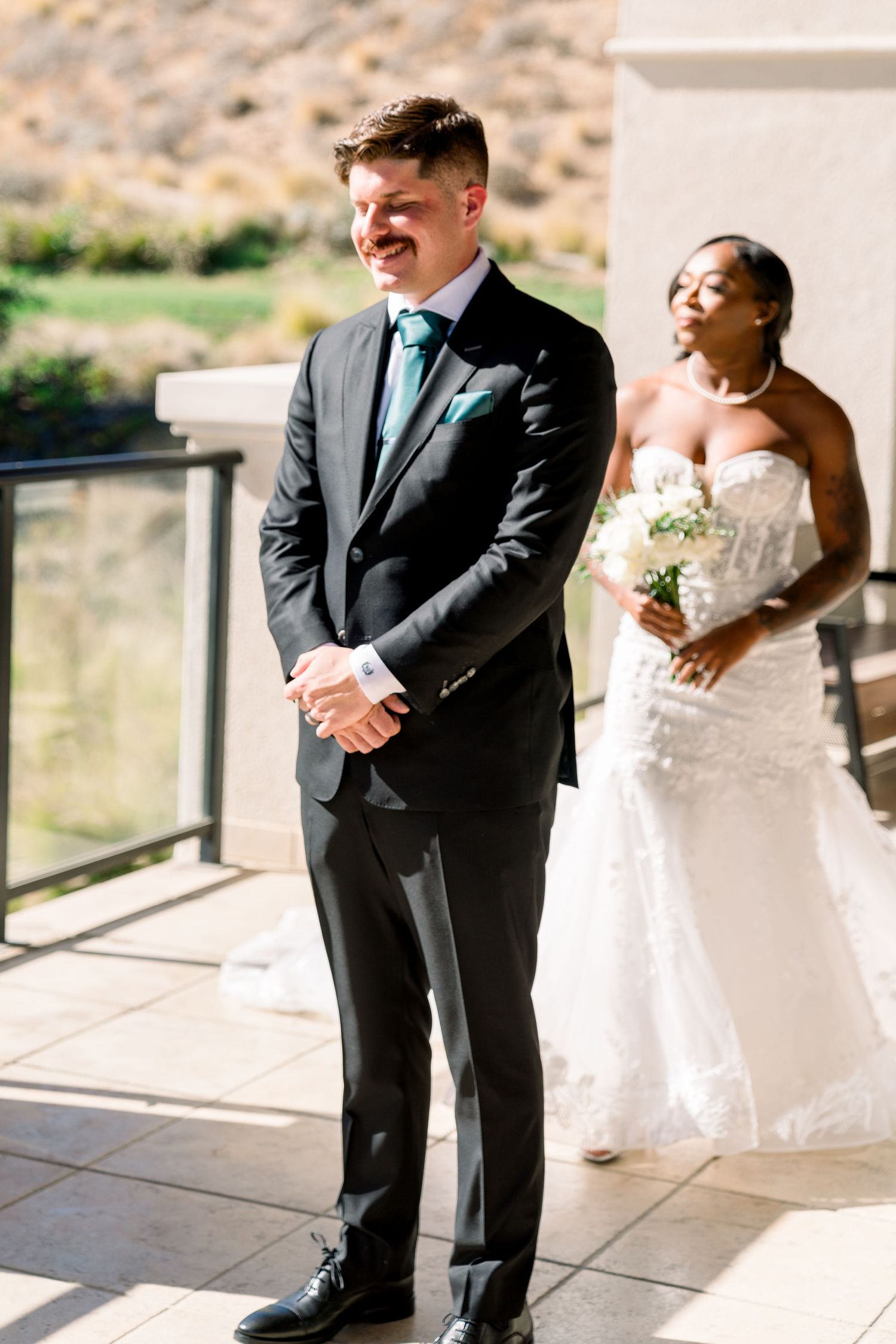 First look wedding moment on outdoor terrace with mountain backdrop.