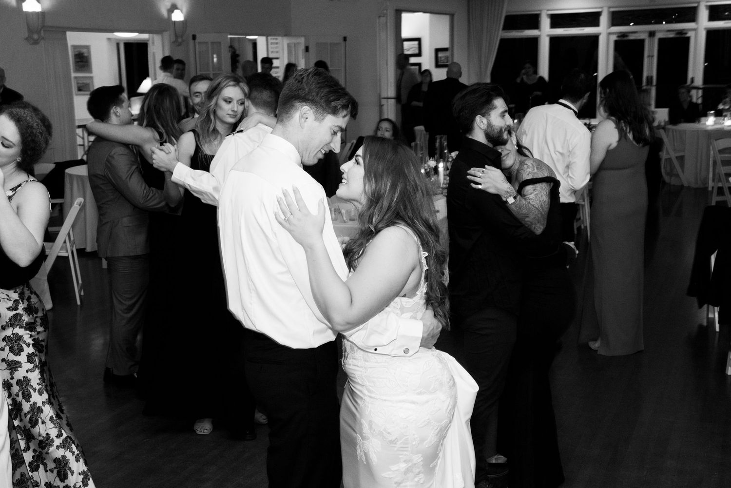Wedding couples dance together during a reception in a dimly lit venue.
