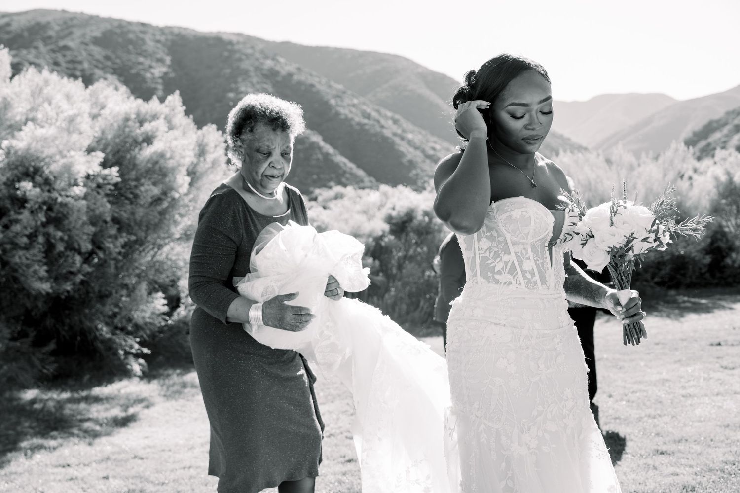 Black and white portrait of wedding preparations with scenic mountain backdrop.