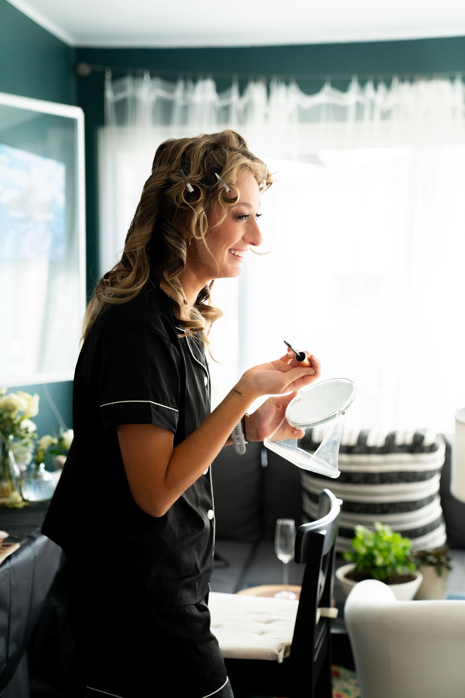 Server in black uniform taking order notes while smiling in a bright restaurant setting with window and decor.