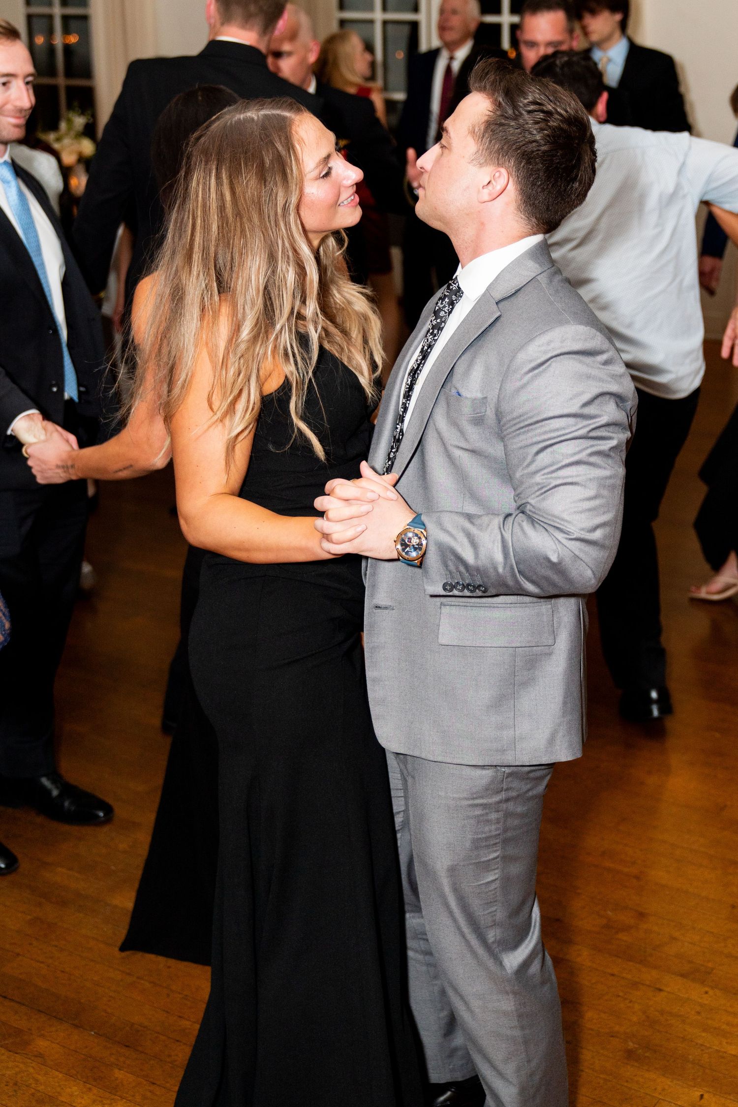 Couple dancing together at formal event with guests in background.