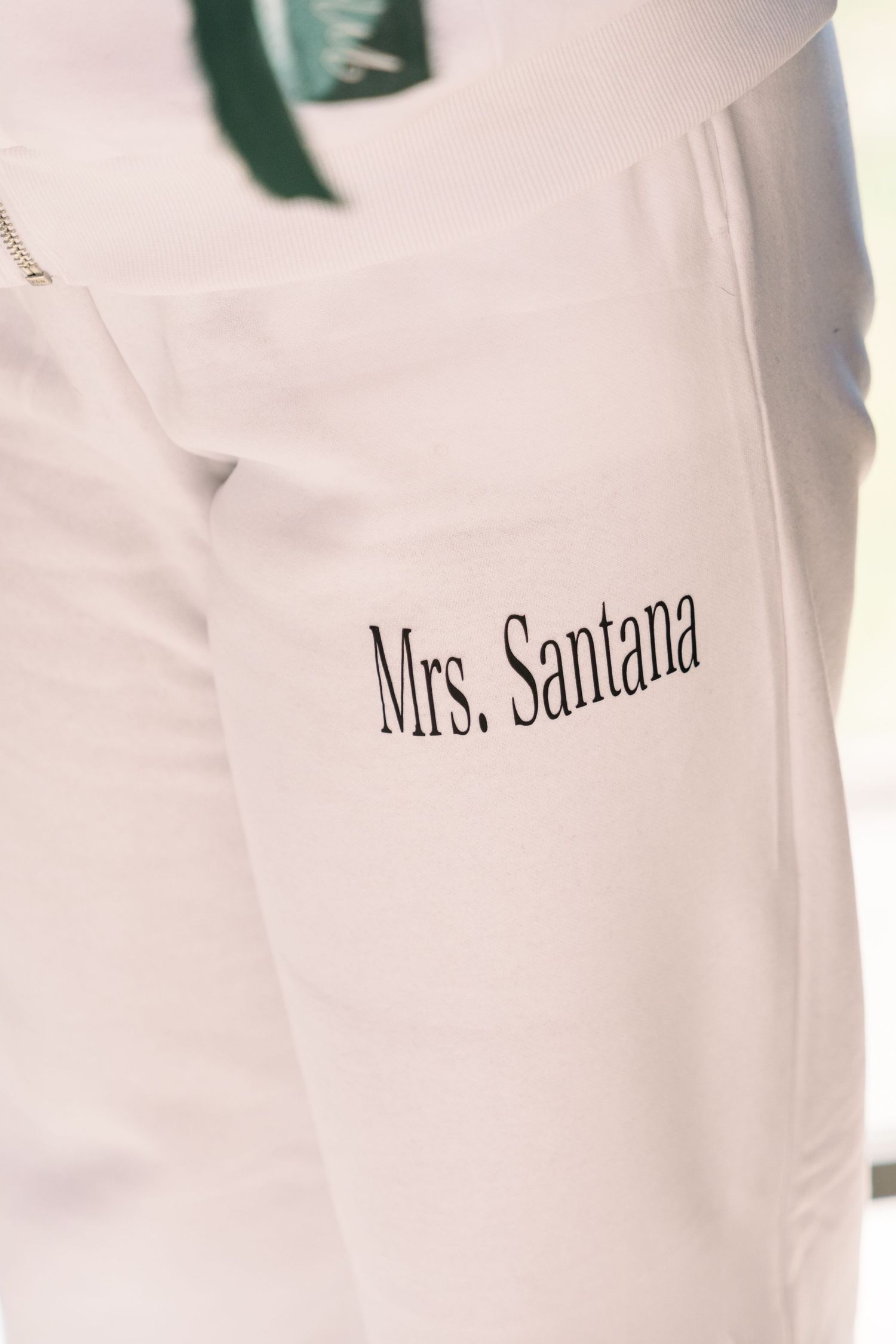 Close-up detail shot of white garment with 'Mrs. Santana' embroidered text.