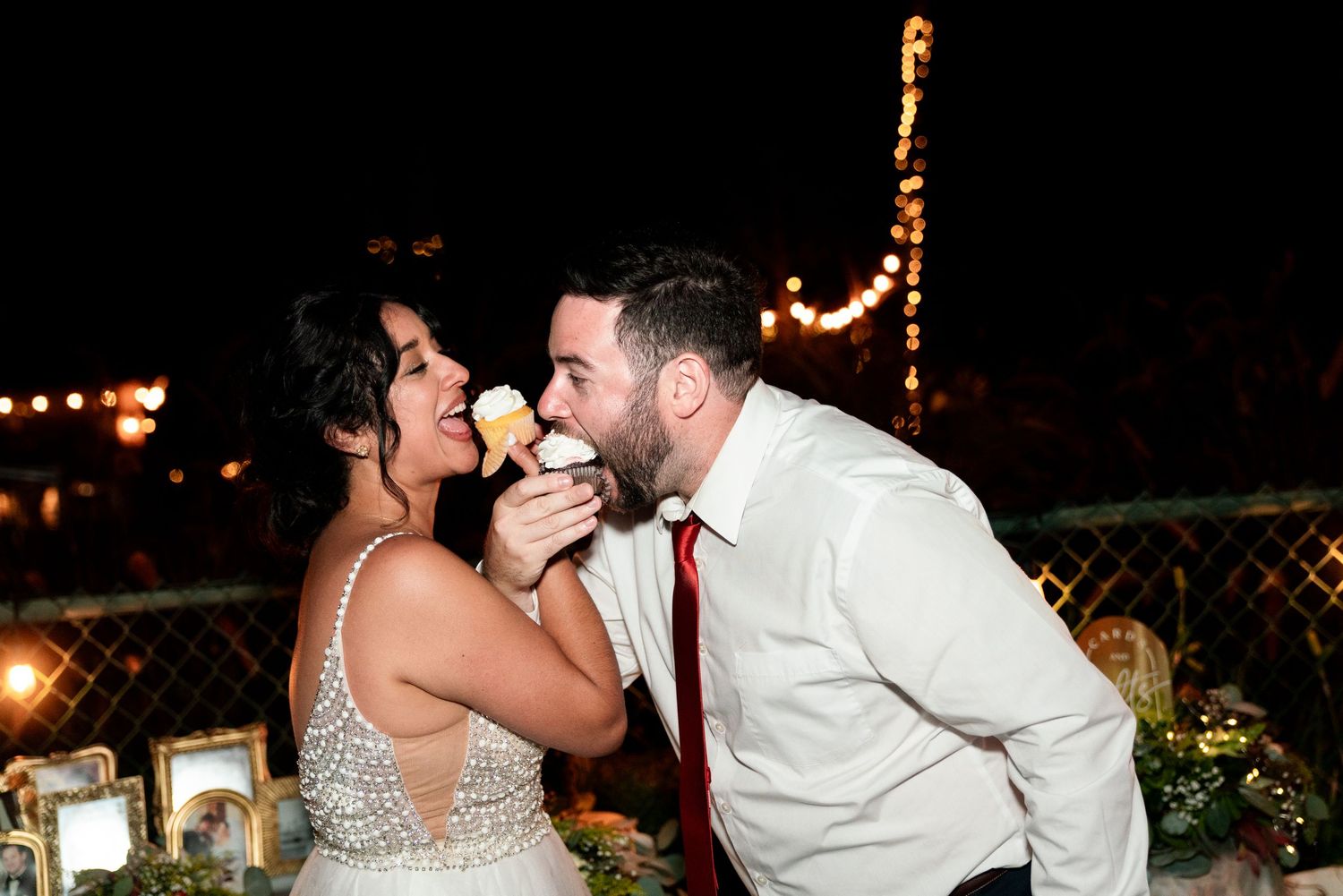 Couple sharing dessert together at nighttime outdoor reception with string lights.