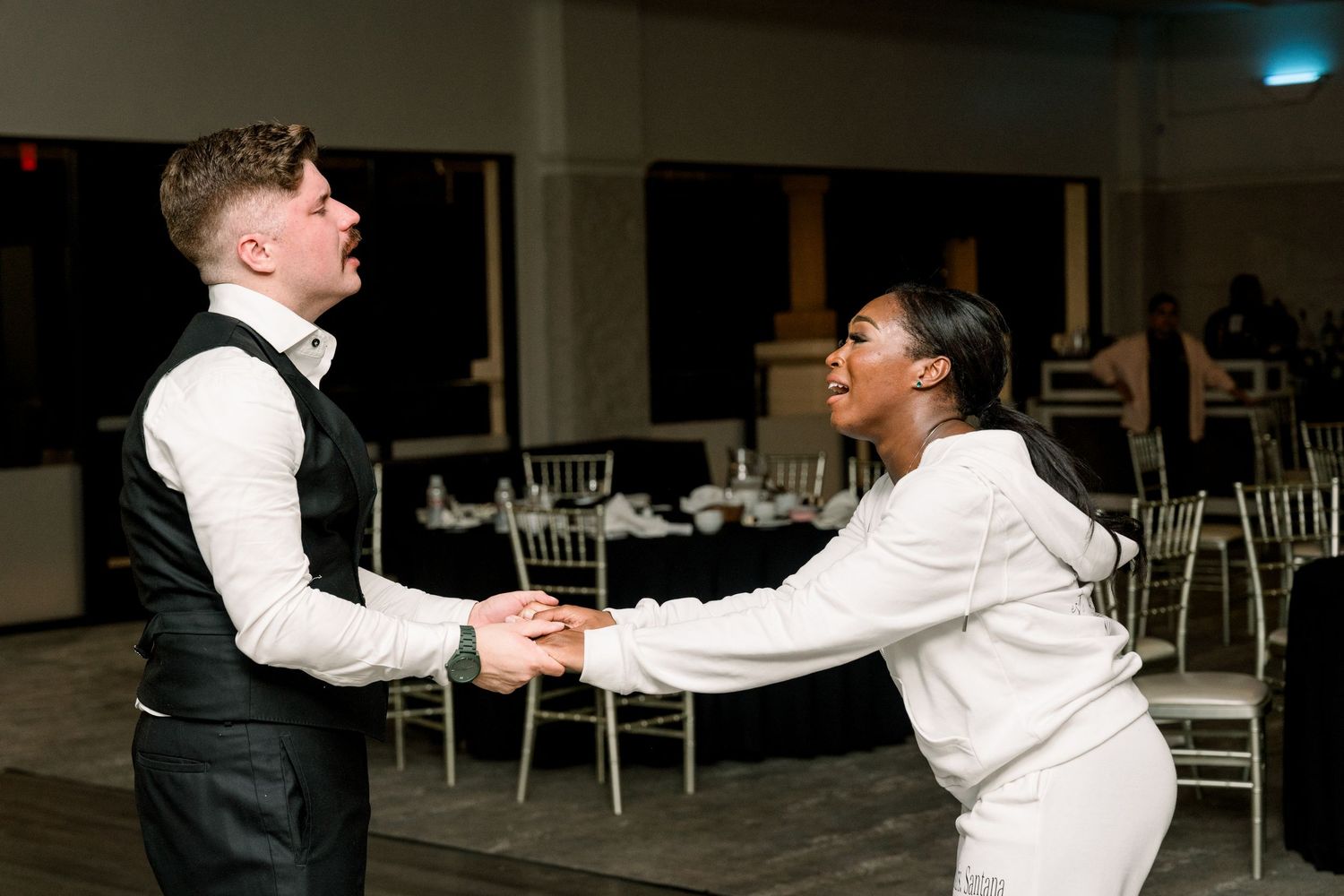 Couple dancing together at wedding reception in indoor venue.