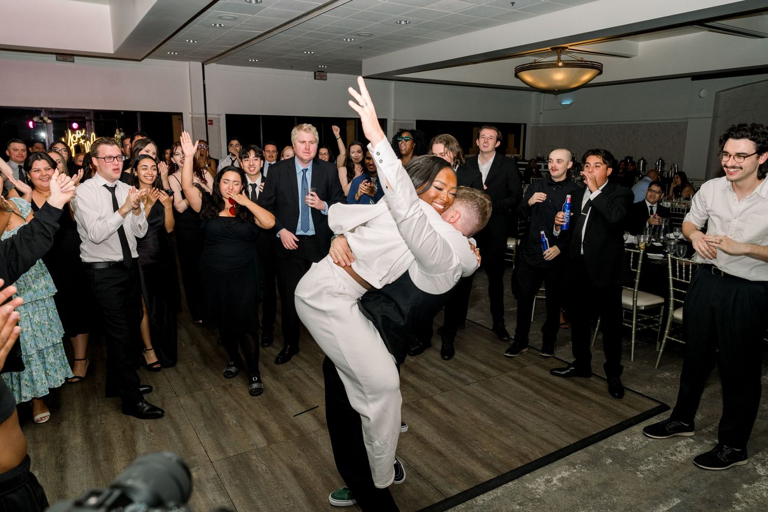 Wedding reception dancing scene with guests forming circle on dance floor.
