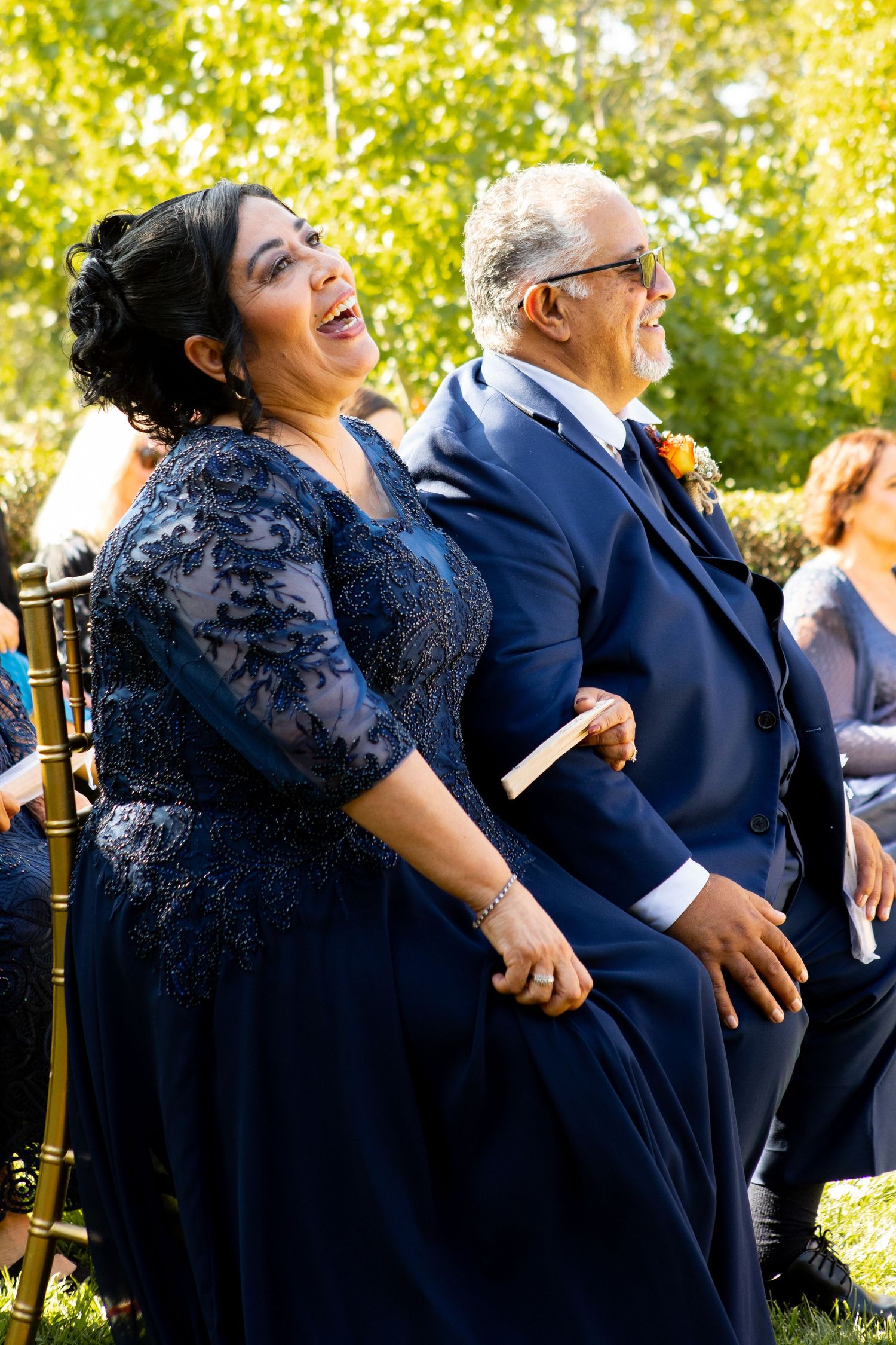 Wedding guests in formal attire share a joyful moment during an outdoor celebration.