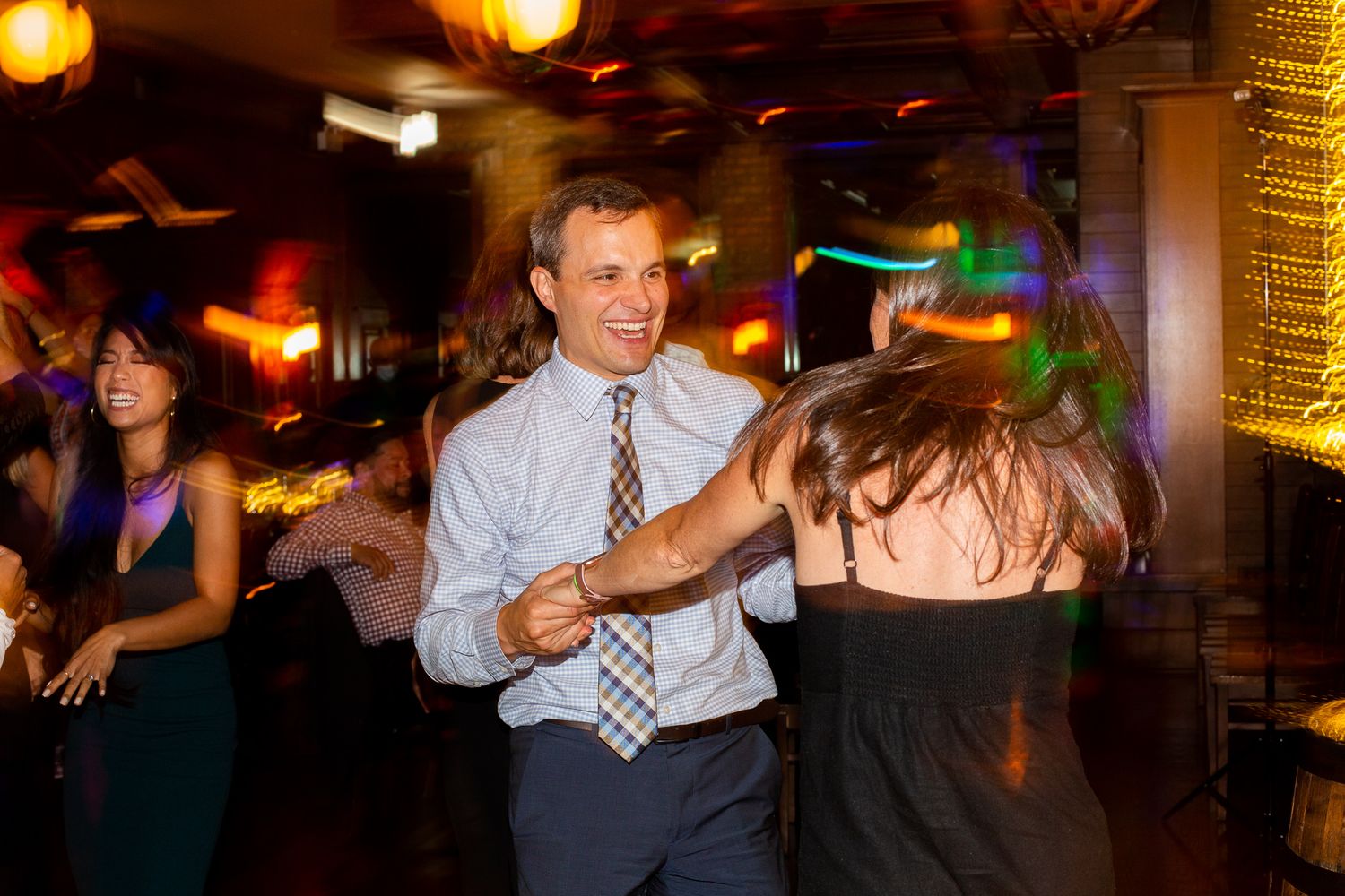 People enjoying dancing at a nightclub with colorful lighting and party atmosphere.