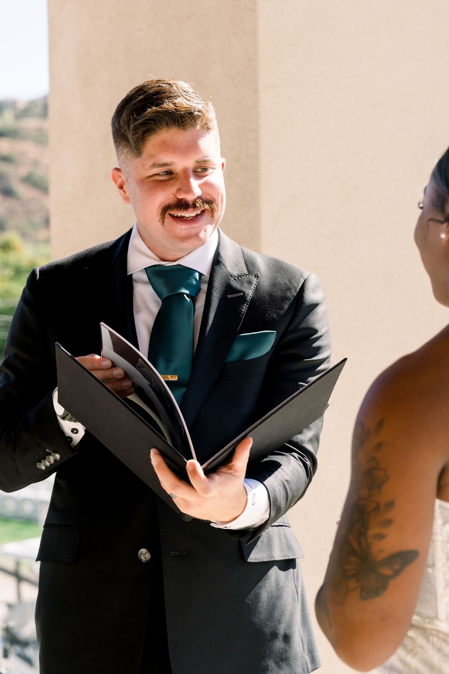 Wedding ceremony moment captured outdoors with officiant holding ceremony book.