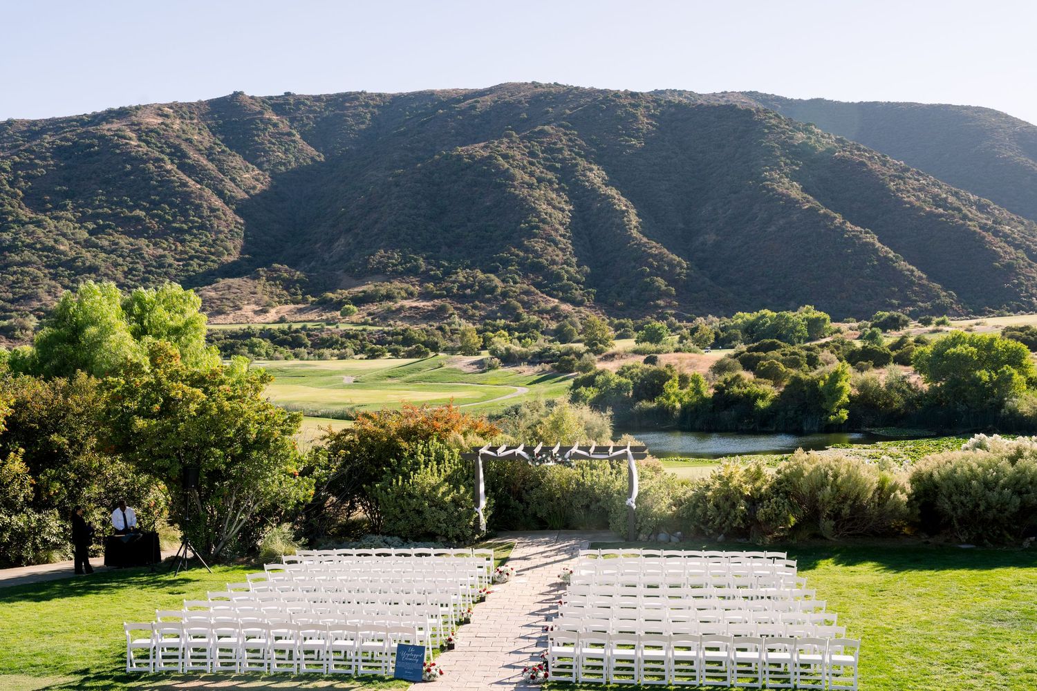 Outdoor wedding venue setup with white chairs and mountain landscape.