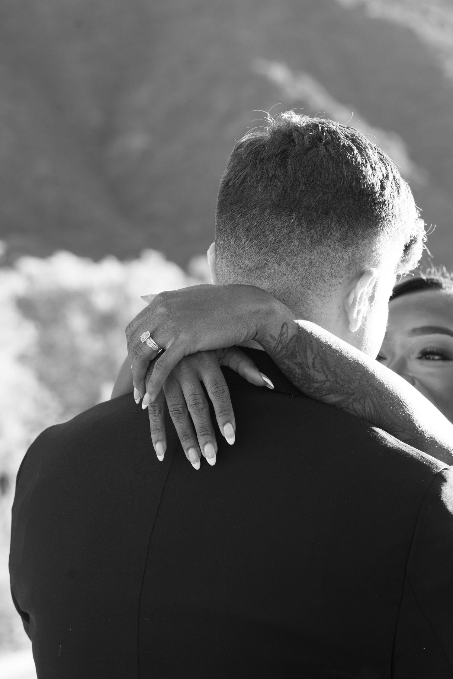 Black and white intimate moment captured showing wedding ring and embrace.