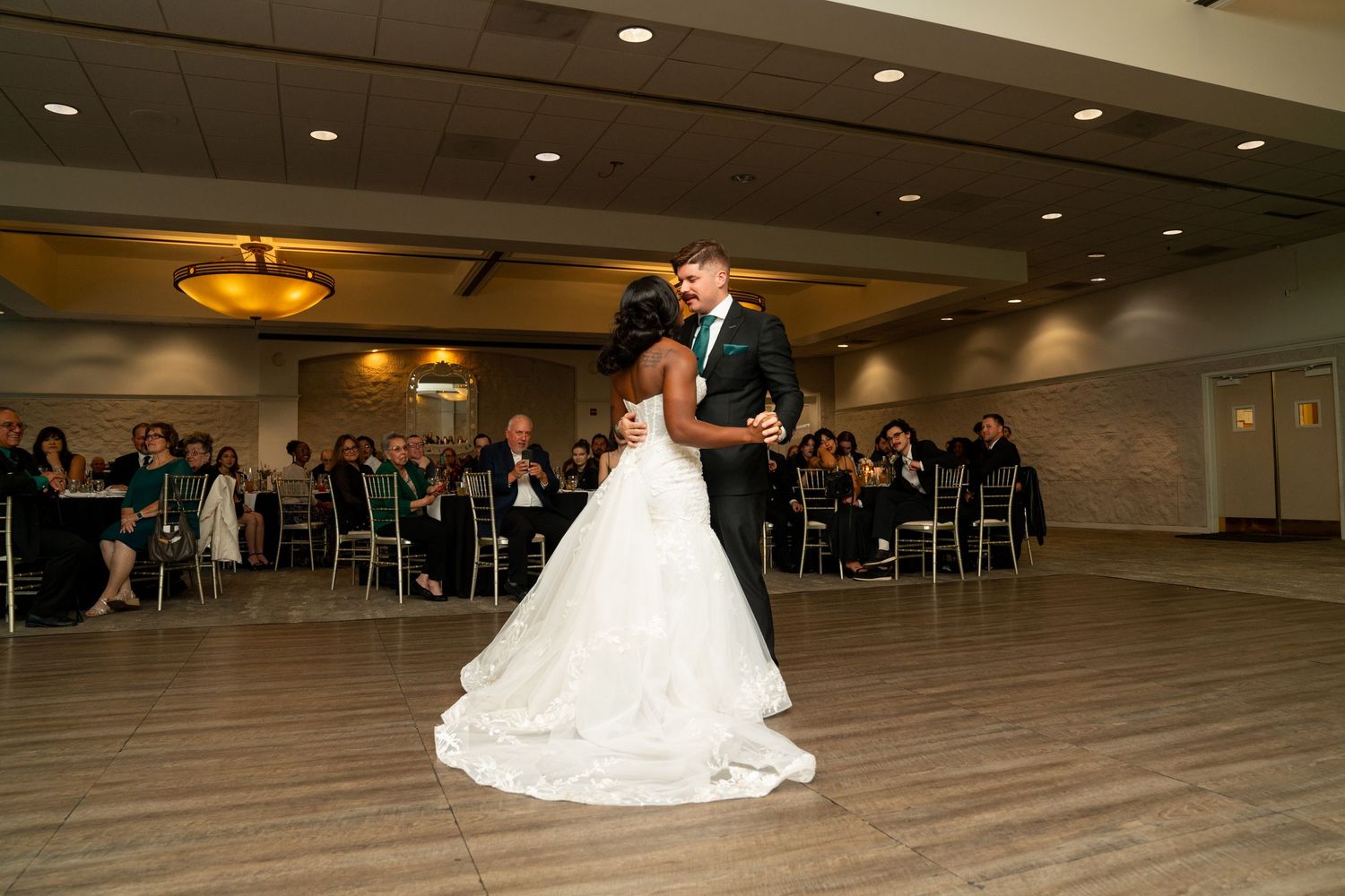 Couple sharing their first dance in elegant ballroom reception venue.