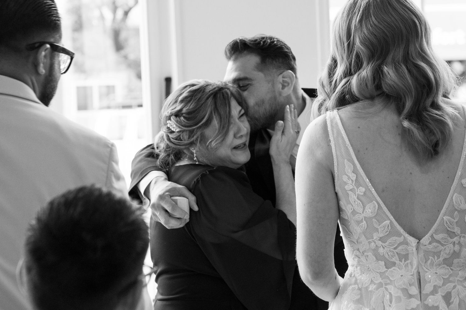 An emotional moment is captured in black and white between wedding guests during a wedding ceremony.