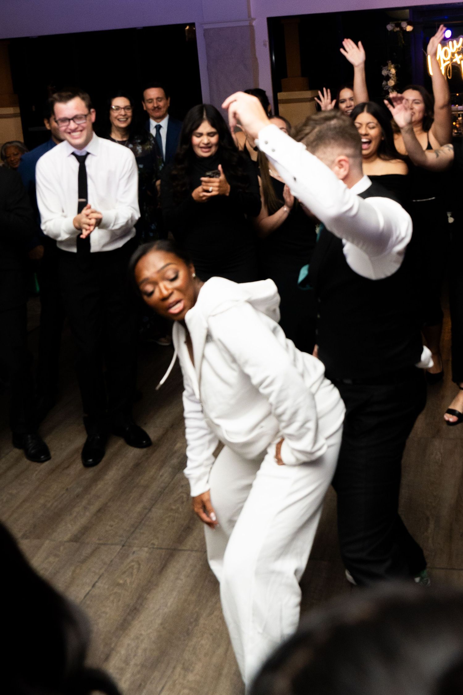 Wedding guests dance and celebrate on the dance floor during an energetic reception party.