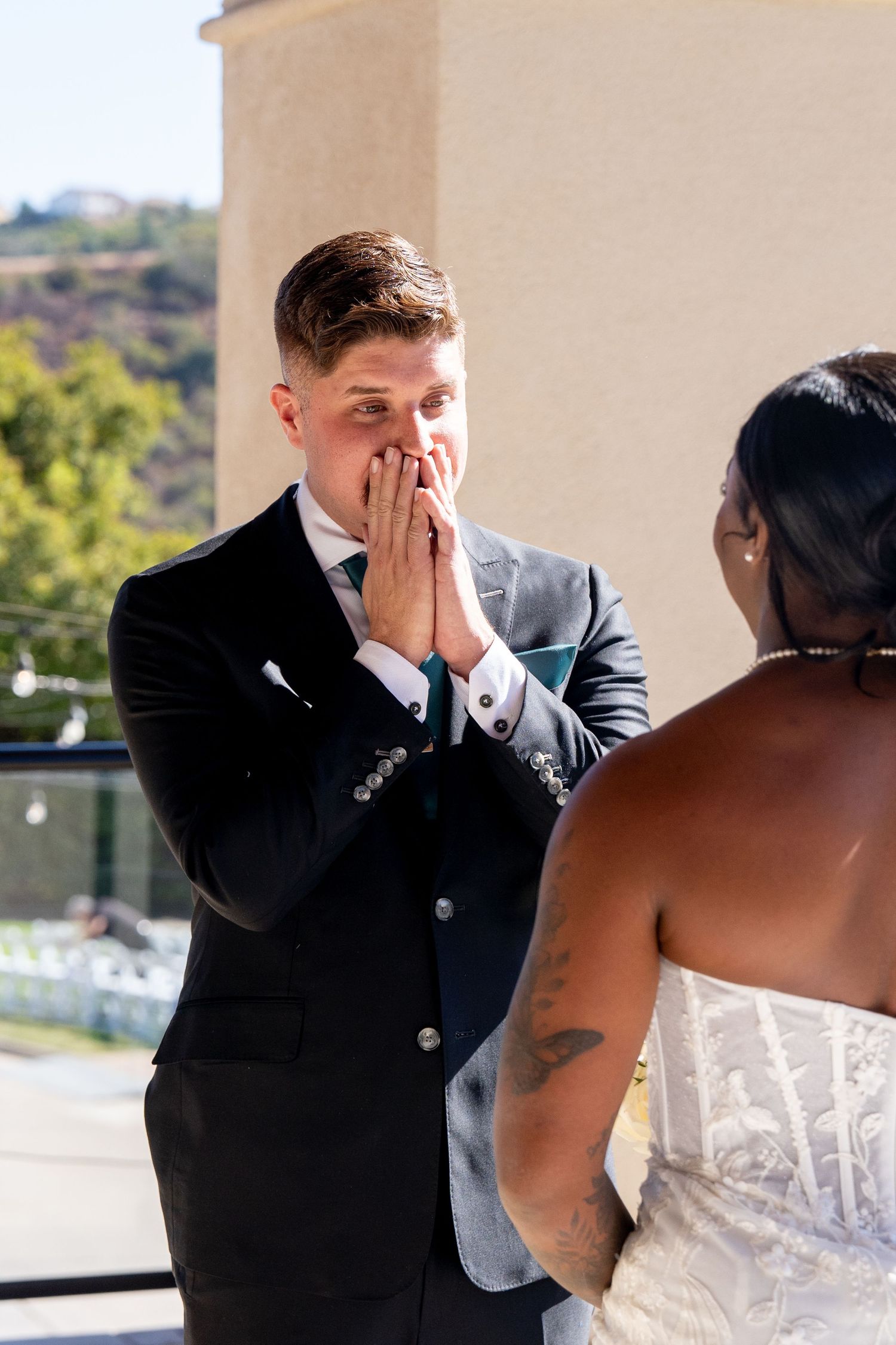 Emotional wedding ceremony moment on outdoor balcony with mountain backdrop.