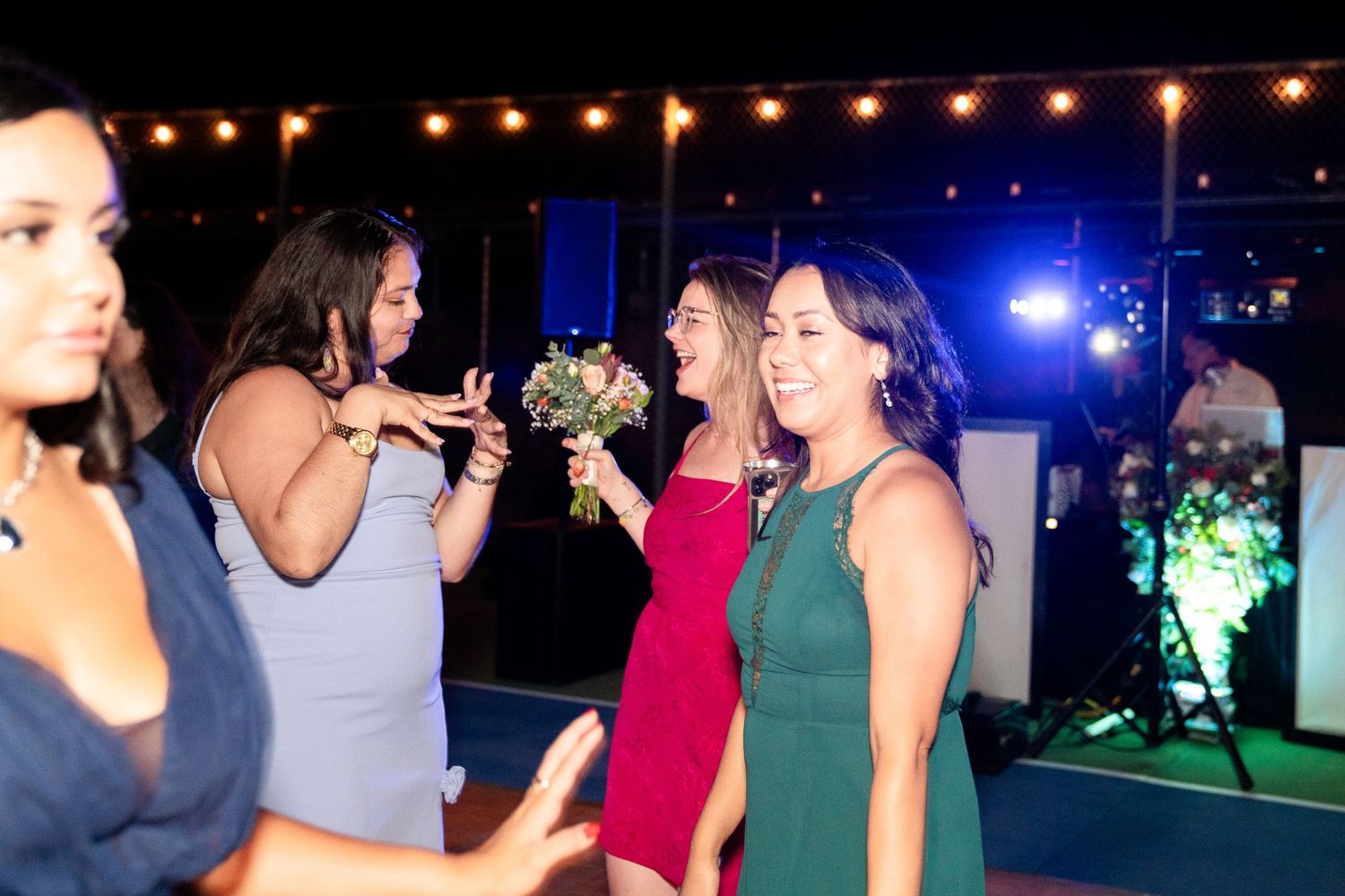 Nighttime wedding celebration with guests dancing and socializing under string lights.