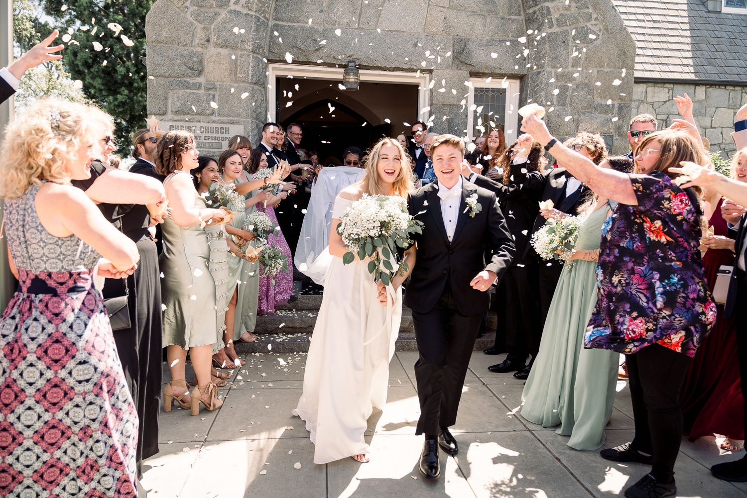 Wedding guests shower newlyweds with confetti as they exit the church entrance in celebration.