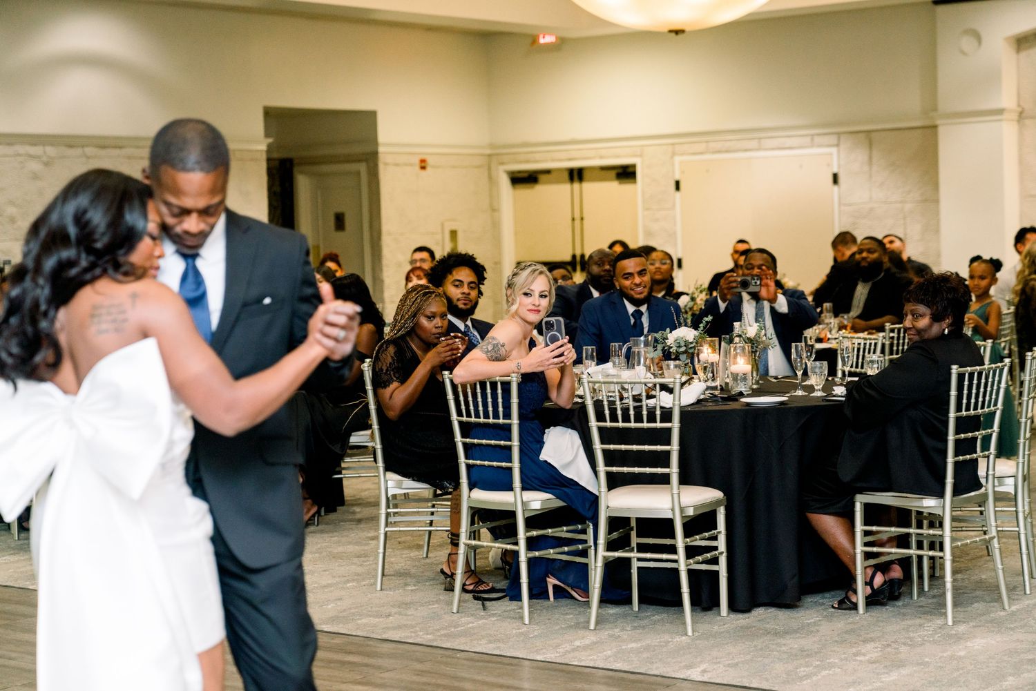Couple sharing their first dance at wedding reception with guests watching.