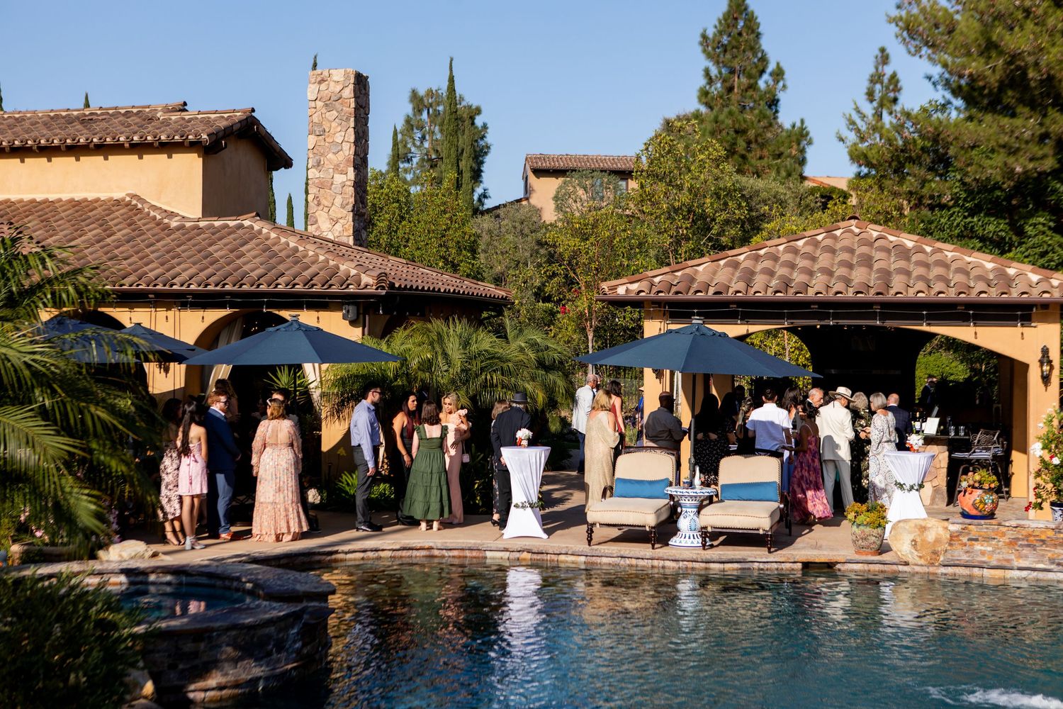 Wedding celebration at a Mediterranean-style venue with guests gathering around a swimming pool.