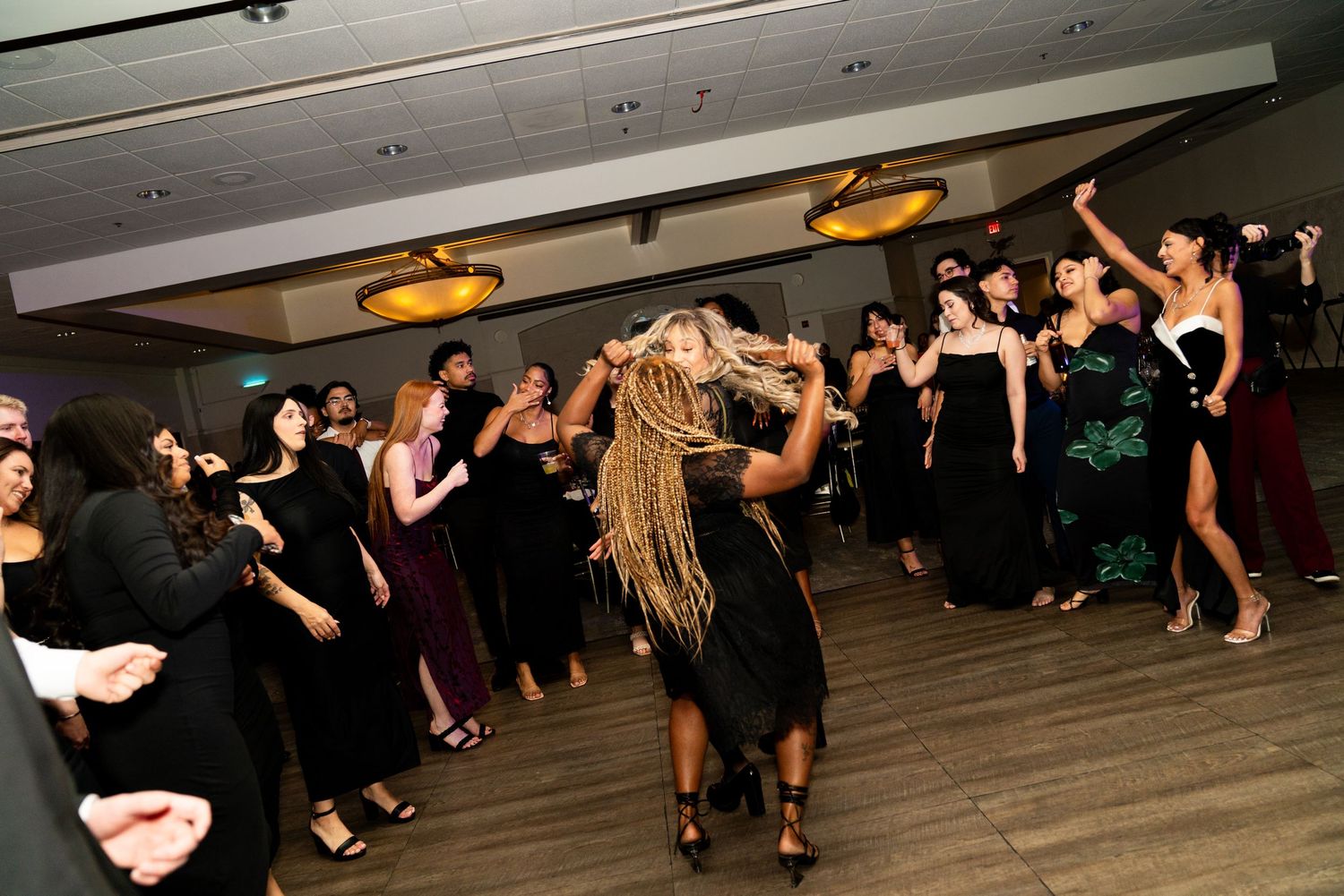 Wedding guests dancing enthusiastically on a wooden dance floor during an evening reception.