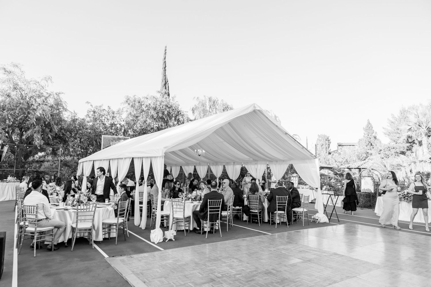 Black and white photo of an elegant outdoor wedding reception under a white tent.