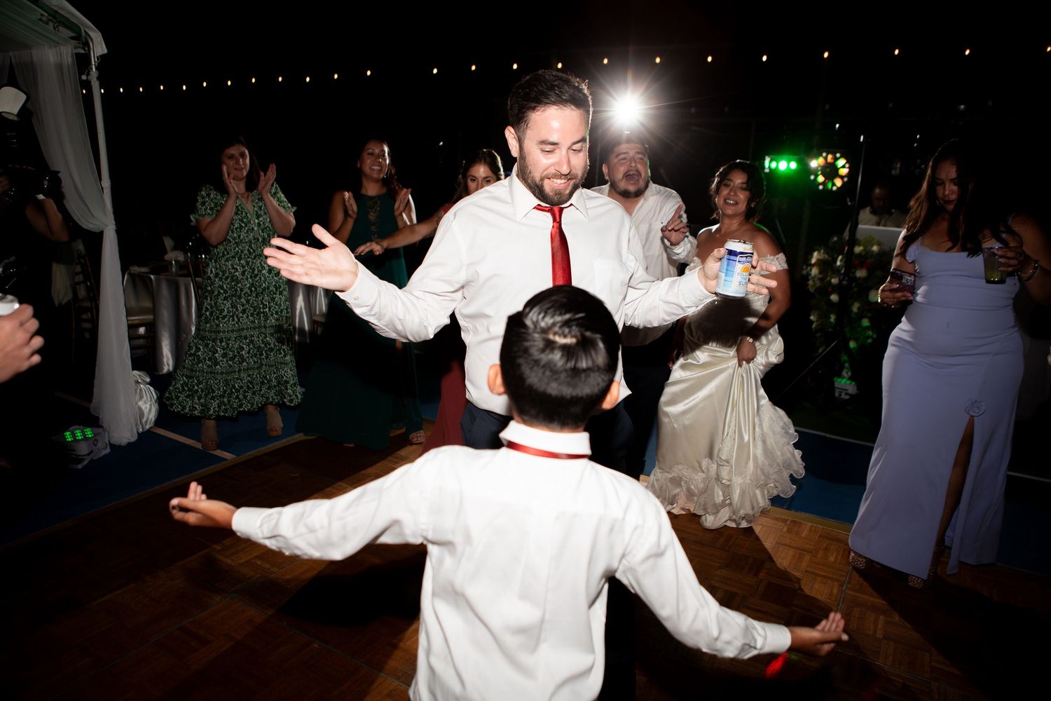 Dancing and celebration on a dimly lit dance floor at wedding reception.