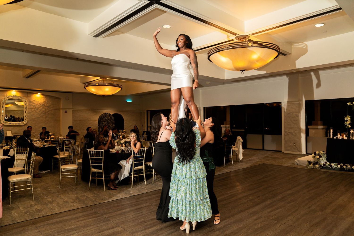 Wedding reception guest being lifted in celebration on the dance floor.