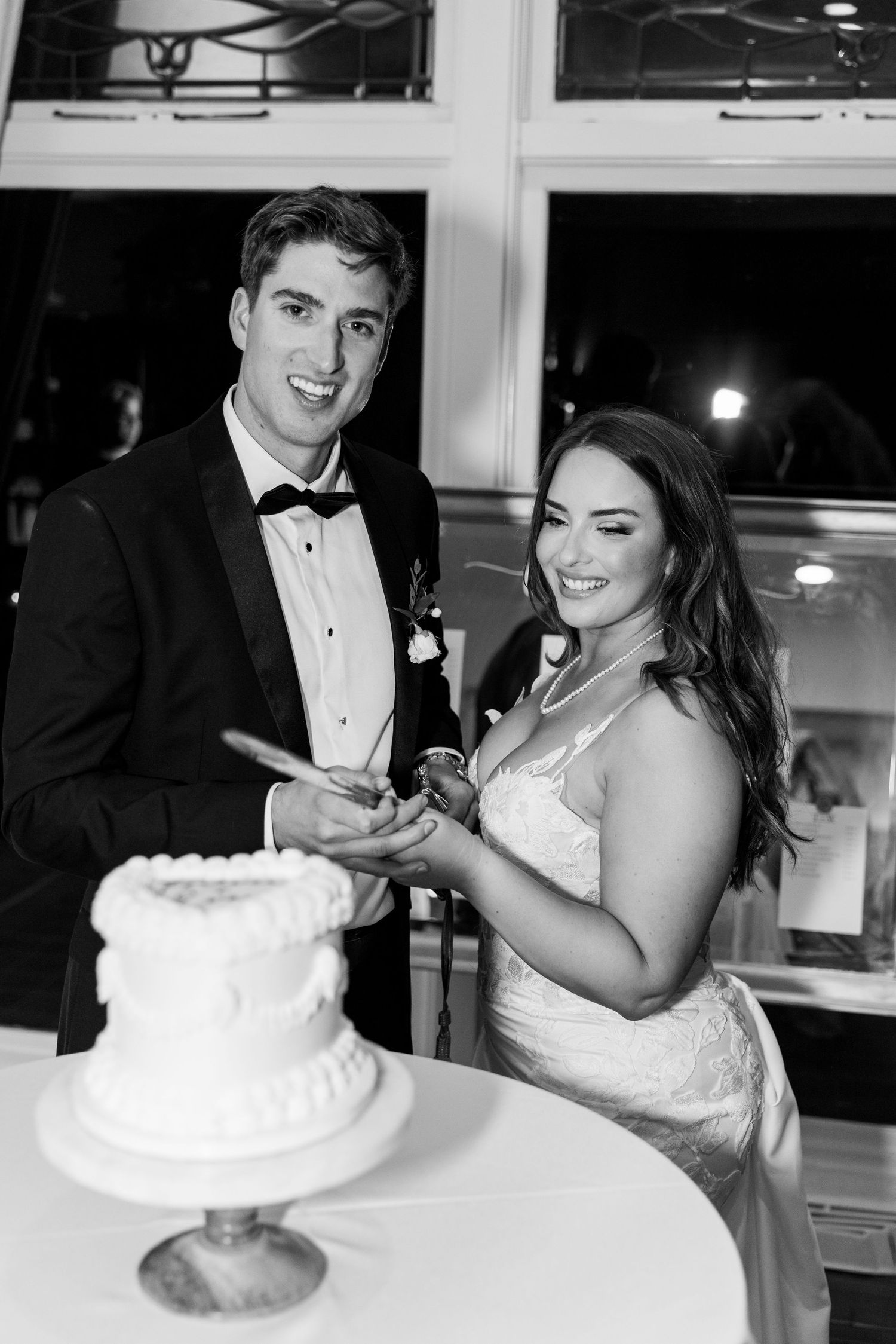 A couple prepares to cut their elegant white wedding cake during their reception celebration.
