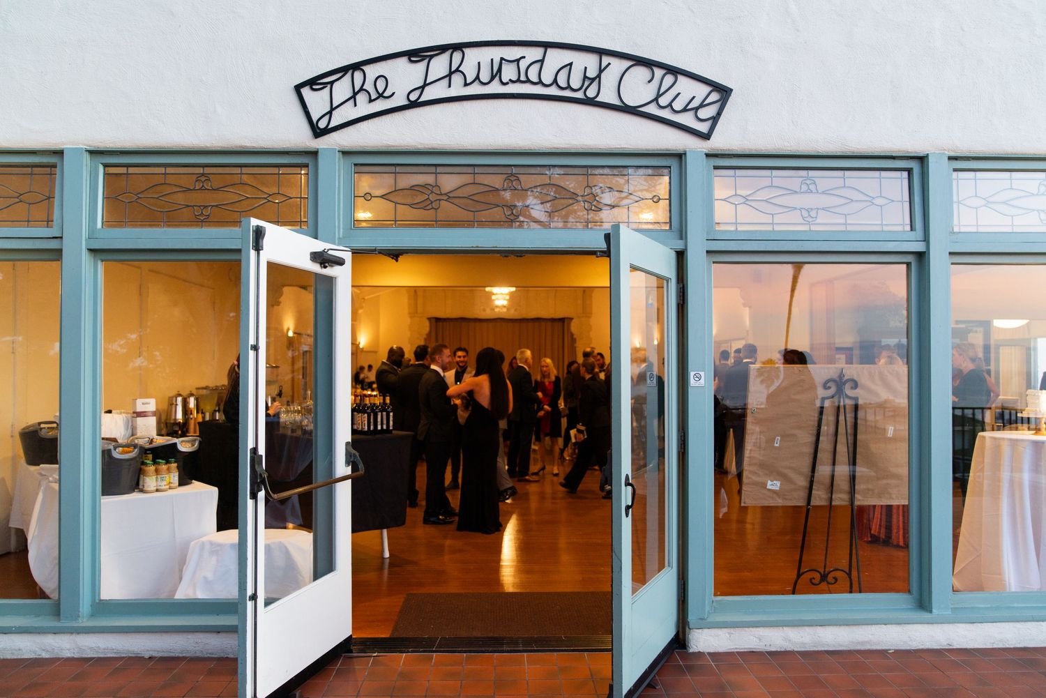 Entrance to The Arcadian Court venue with blue-framed doors and people gathering inside.