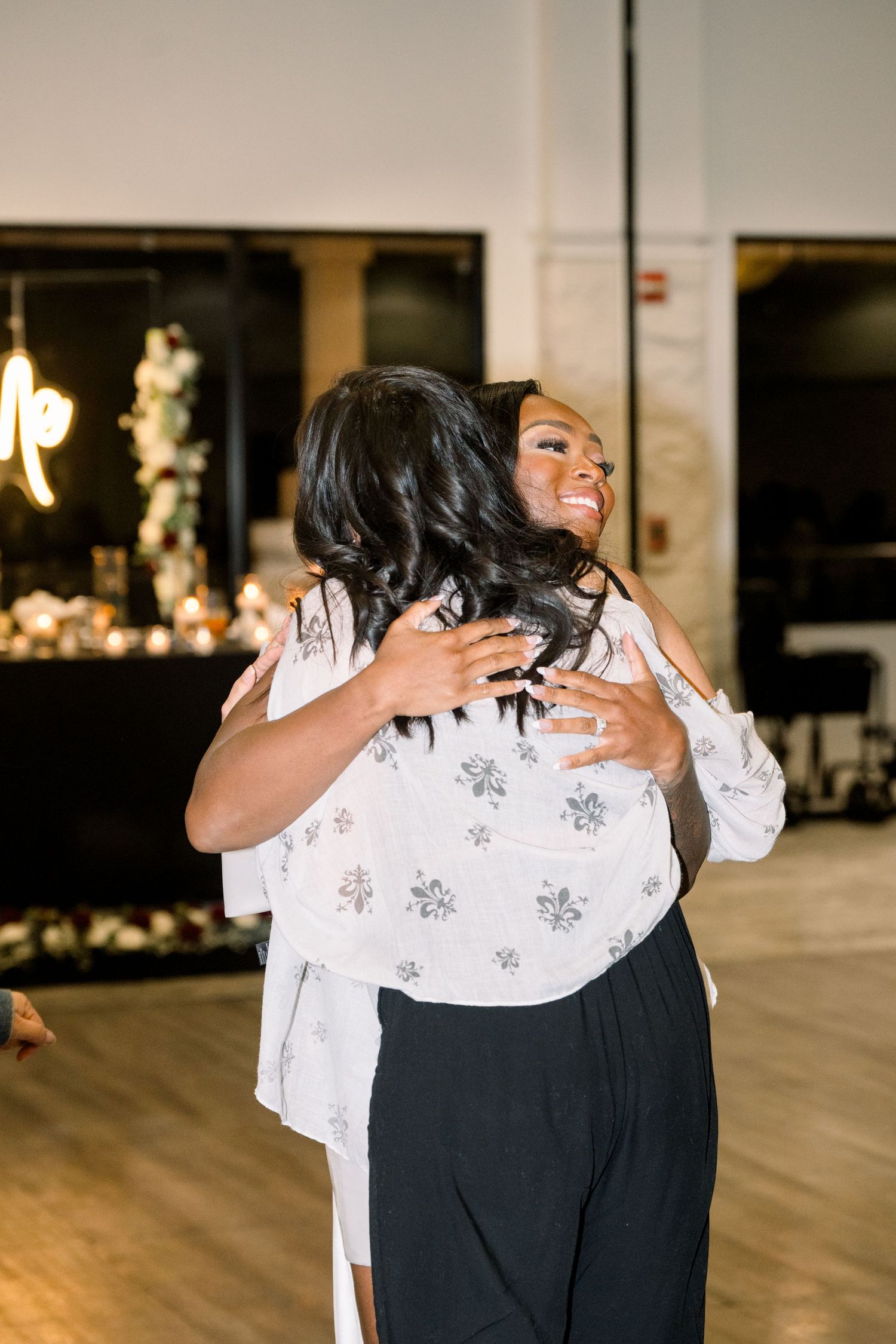 Two people share an emotional embrace while dancing in an elegant venue with warm lighting.